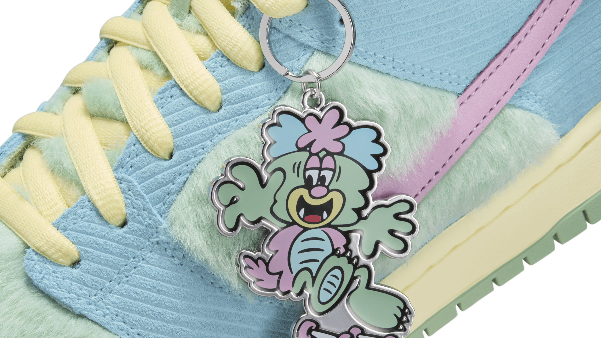 A colorful sneaker with pastel blue, green, and pink hues, featuring a cartoon character keychain with a playful expression.