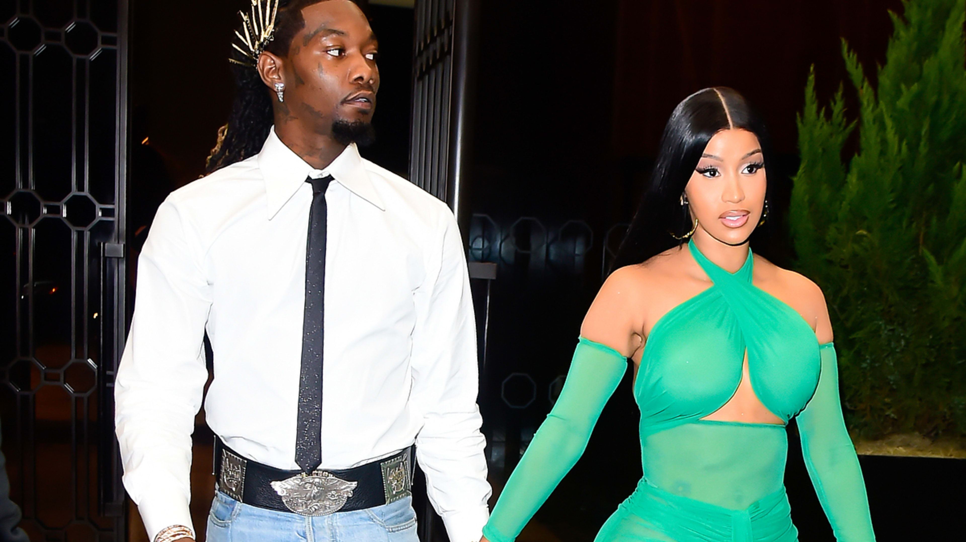 Offset and Cardi B hold hands as they walk; Offset wears a white shirt and jeans, while Cardi B stuns in an elegant green gown