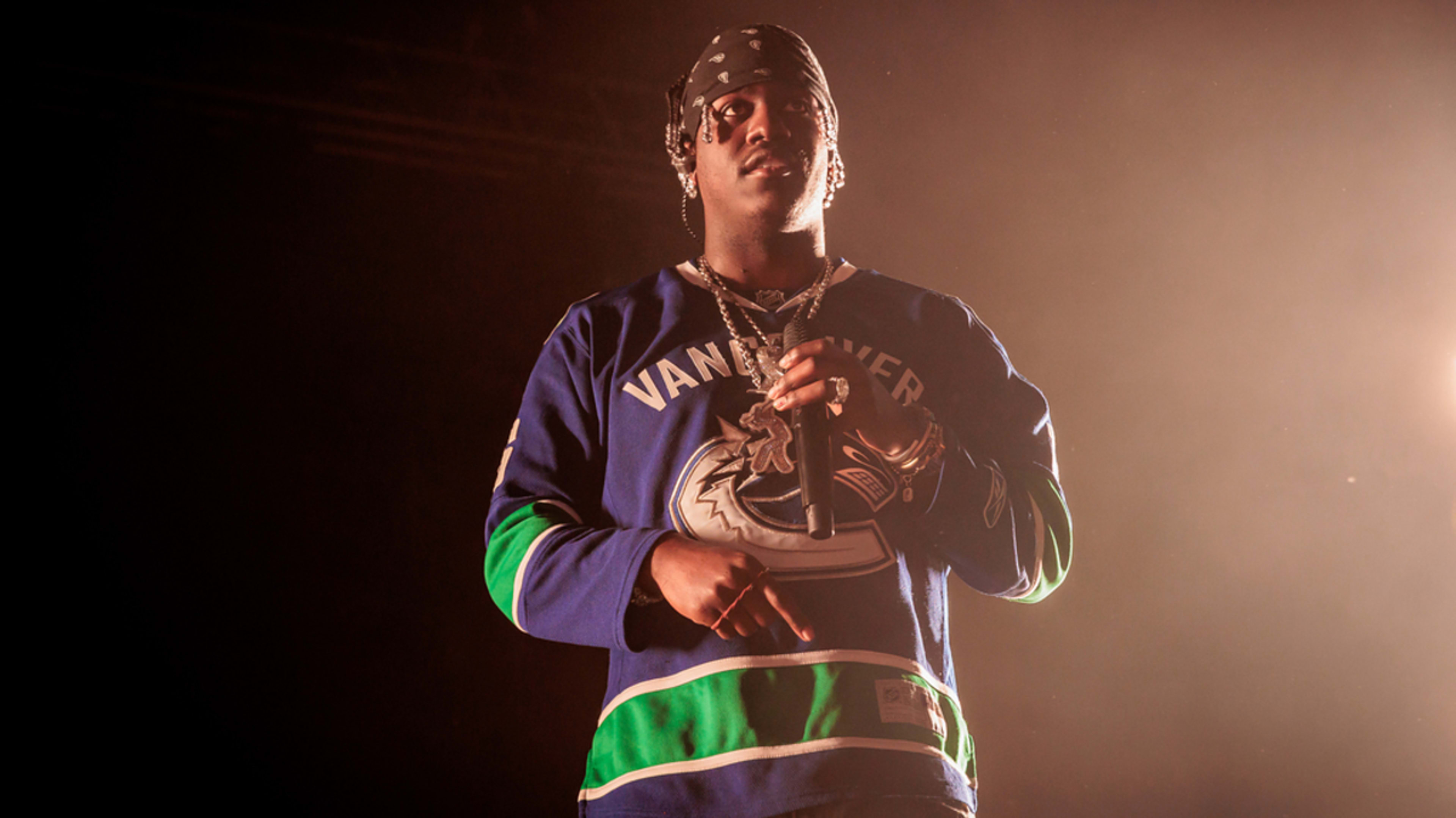 Rapper Lil Yachty performing on stage, wearing a blue Vancouver Canucks hockey jersey and a bandana