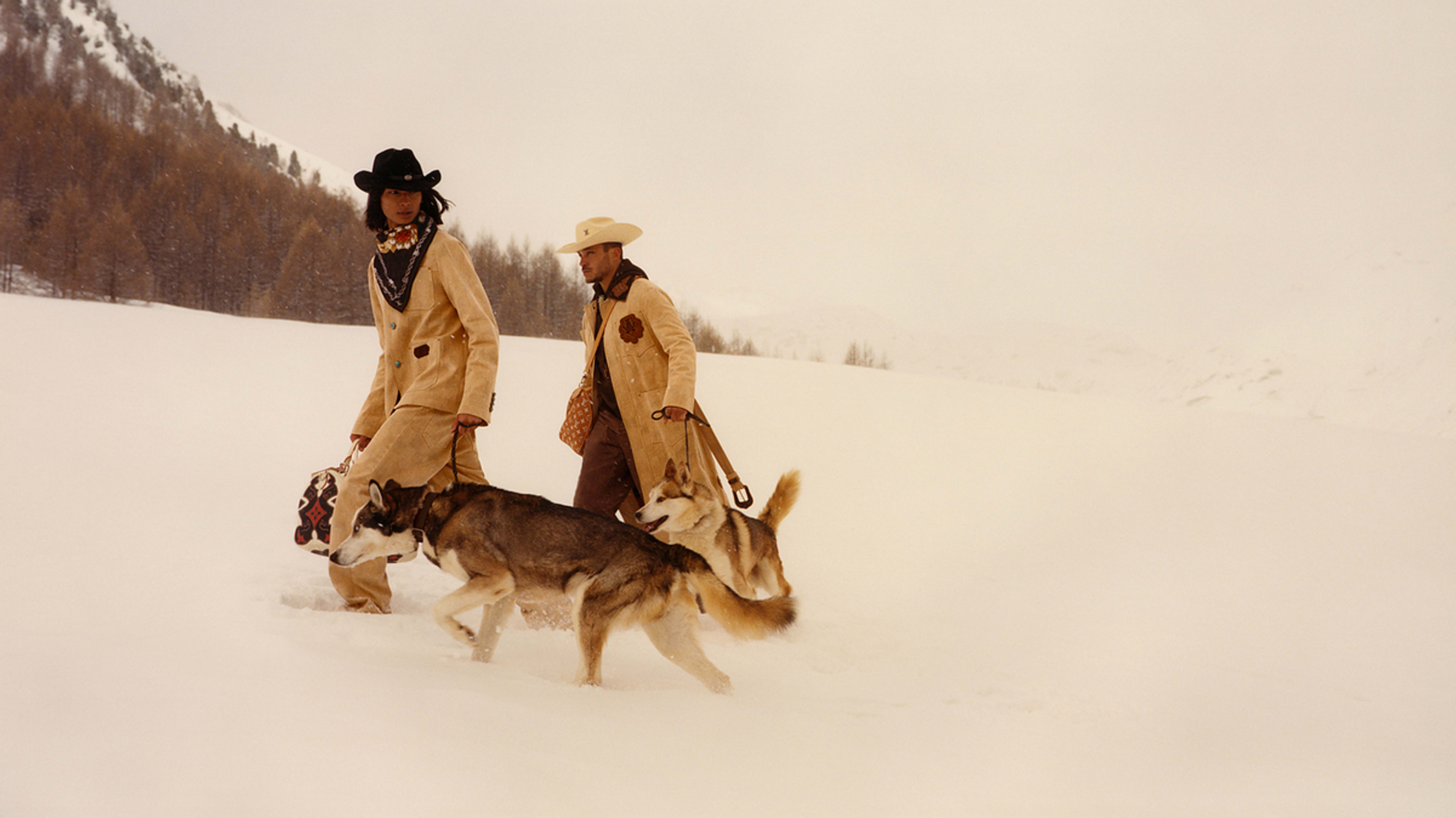 Two people in cowboy attire walk Huskies in a snowy landscape. The scene illustrates Western fashion in a winter setting, demonstrating outdoor style and canine companionship