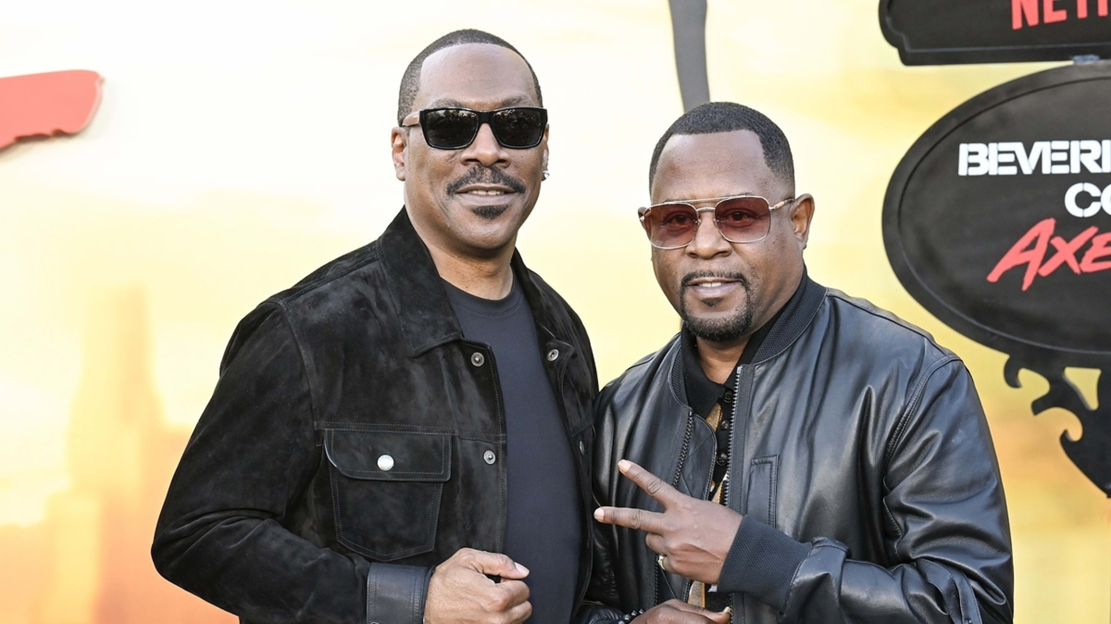 Eddie Murphy and Martin Lawrence pose together at a red carpet event, both wearing sunglasses and stylish black jackets