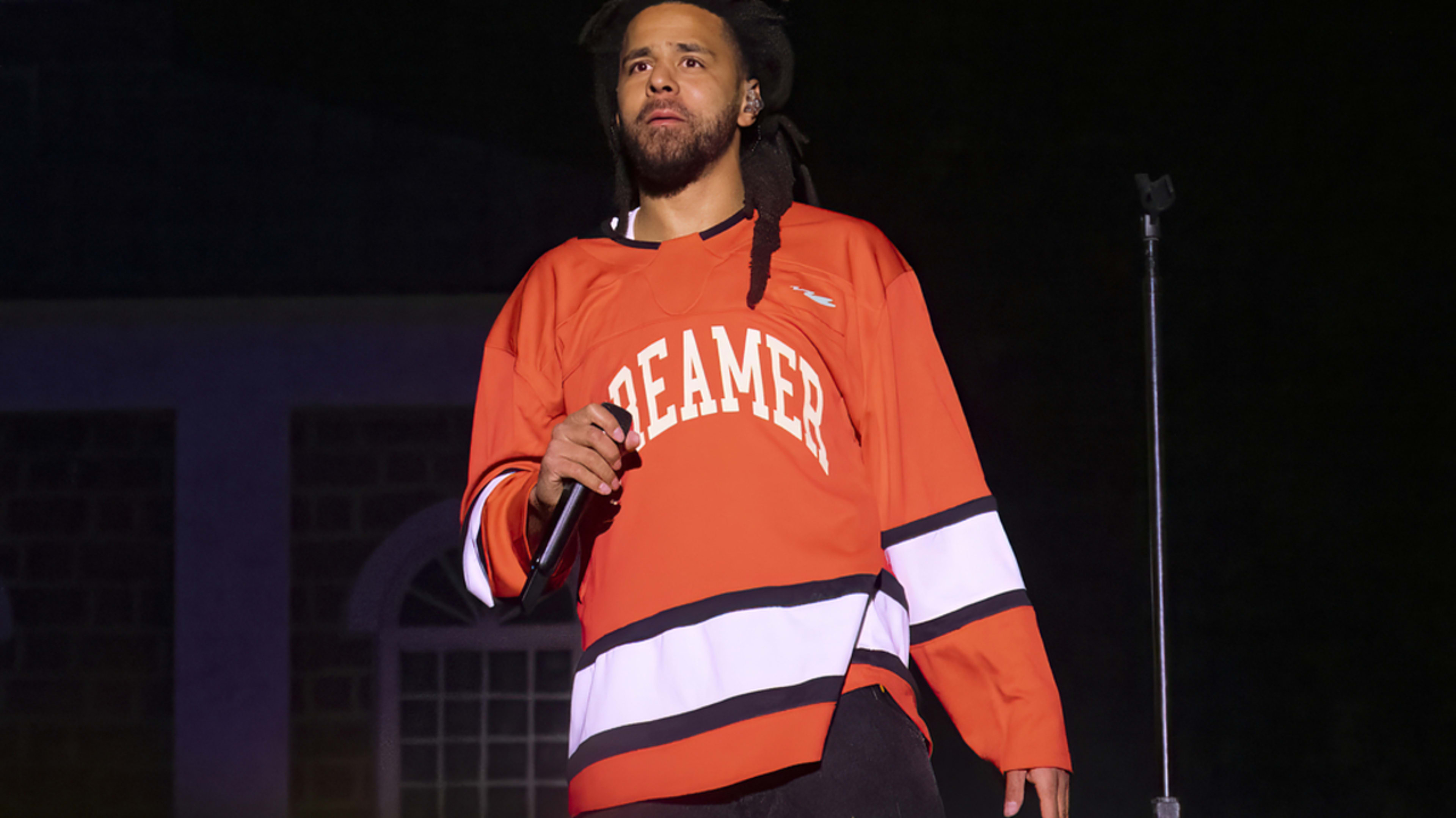 J. Cole performs on stage wearing a 'Dreamer' jersey during a music event