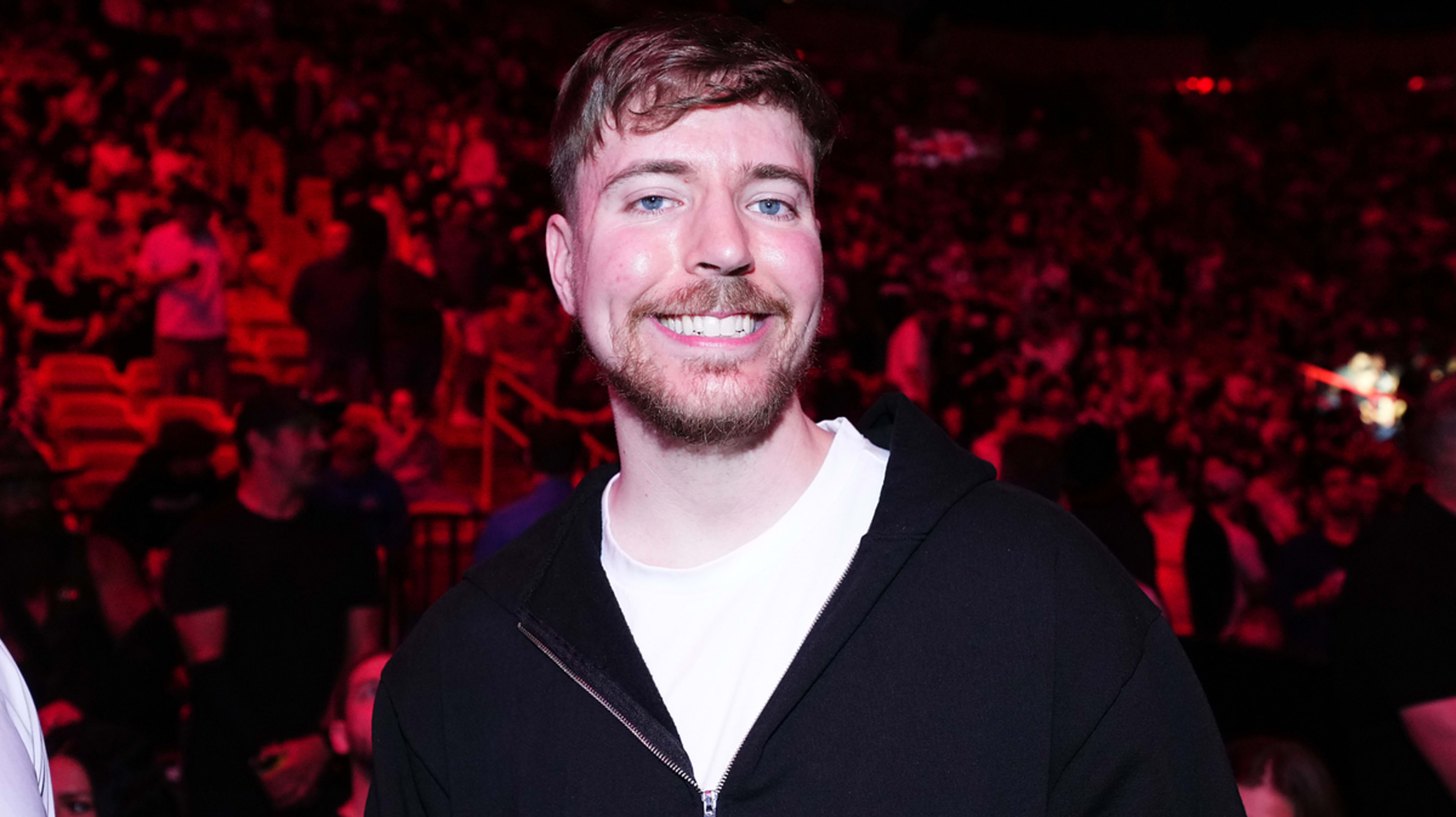 A man in casual attire smiles at a crowded event venue