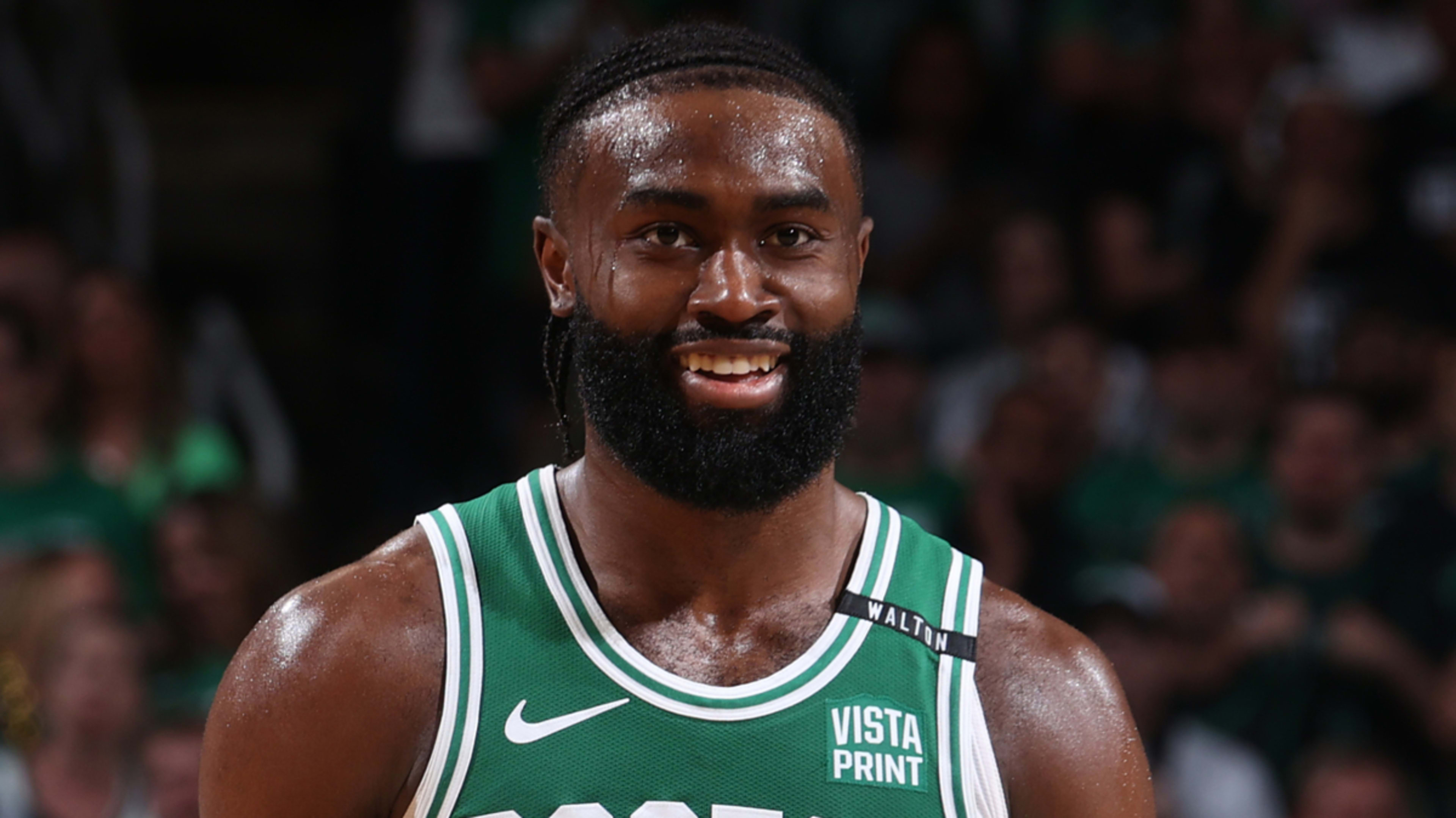 Jaylen Brown, NBA player, smiling on the basketball court wearing a sleeveless jersey