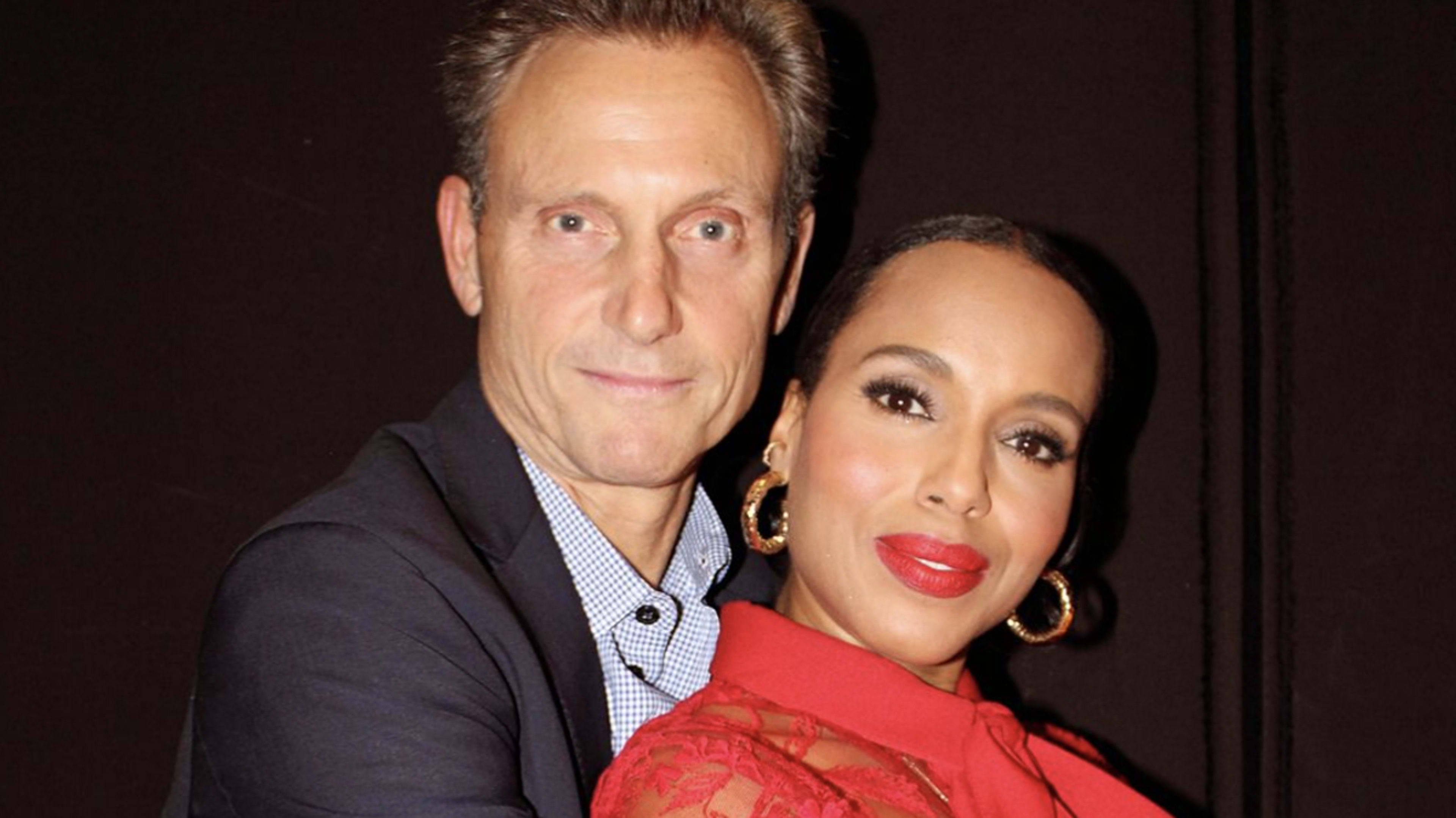 Tony Goldwyn and Kerry Washington pose together, with Tony in a suit and Kerry in an elegant lace dress. Both smile warmly at the camera