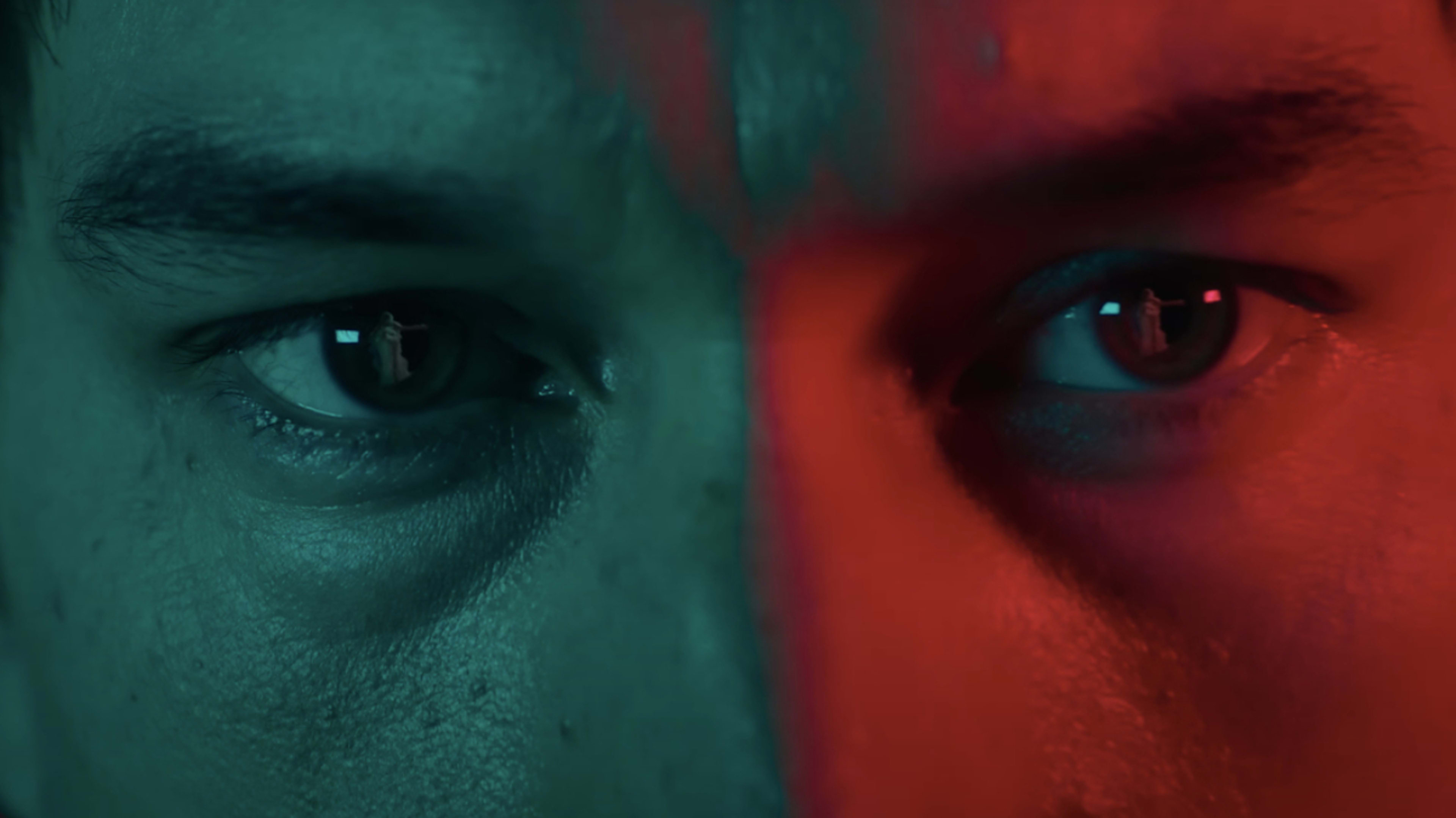 Close-up of a person's eyes with one side lit in blue and the other in red, suggesting contrast