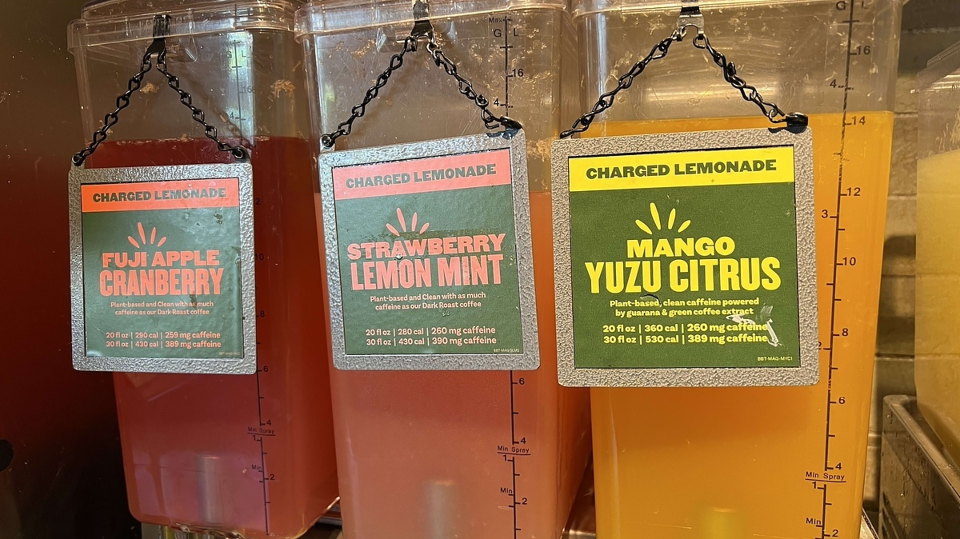 Three dispensers labeled "Charged Lemonade" in flavors: Fuji Apple Cranberry, Strawberry Lemon Mint, Mango Yuzu Citrus