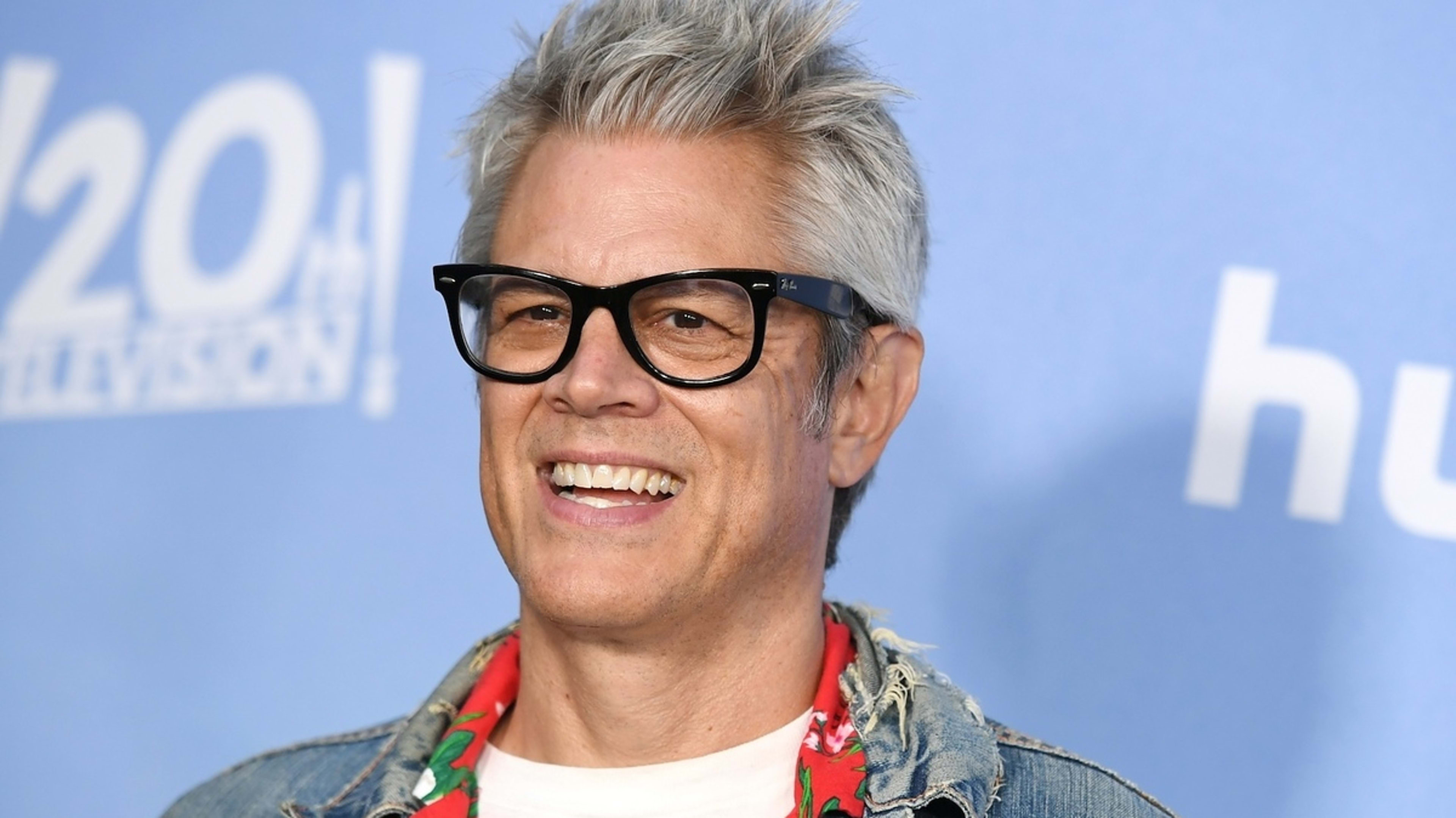 Man smiling in glasses, wearing a jacket with floral print and denim trim