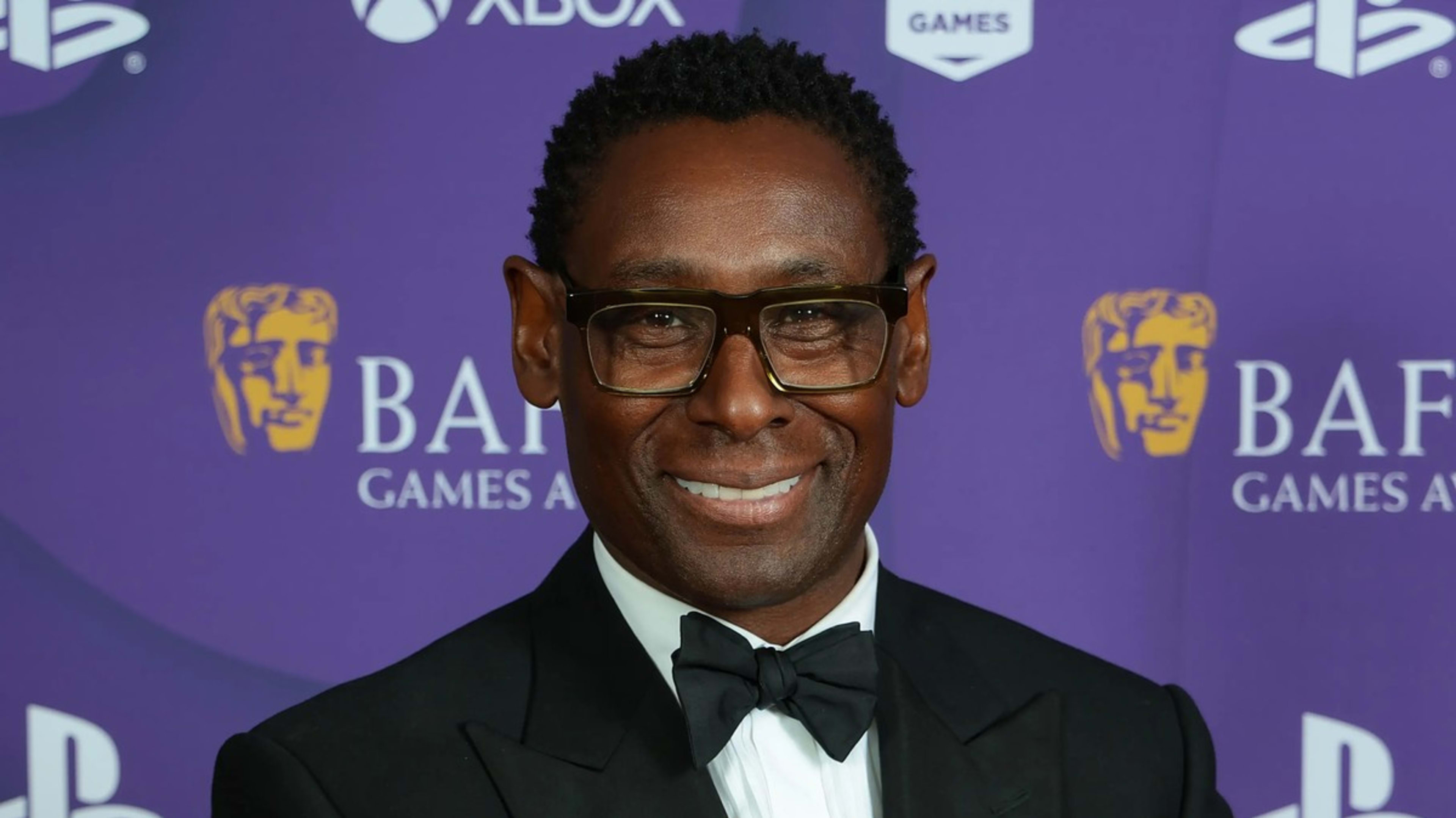 Man smiling at BAFTA Games Awards in black tuxedo and bow tie