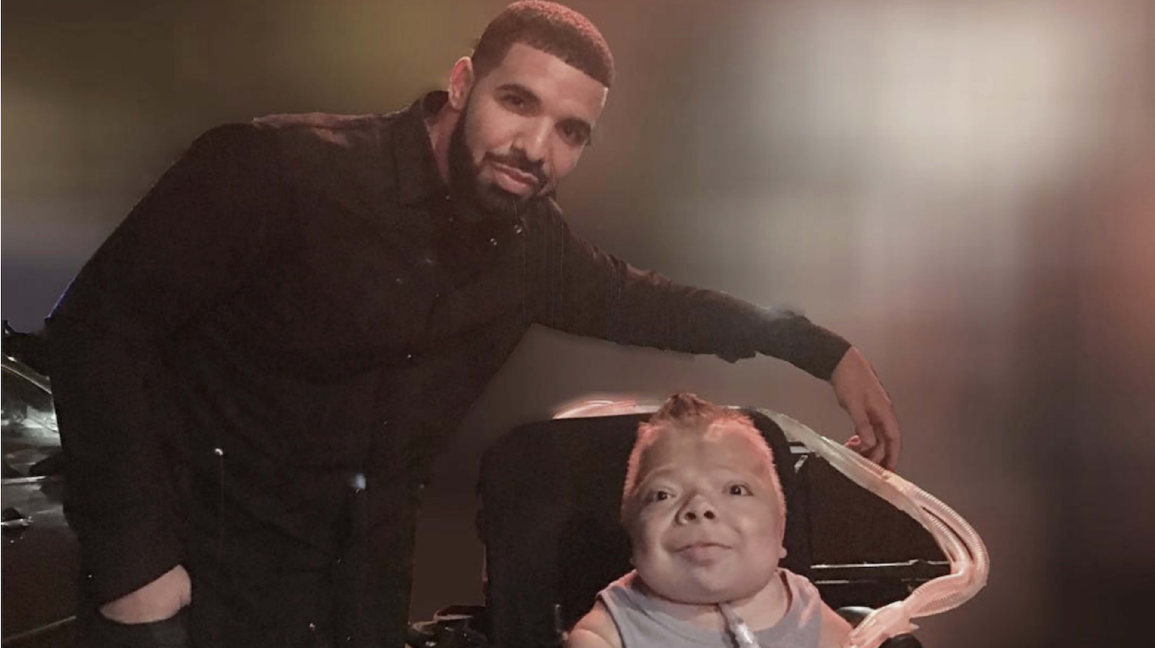 Drake stands next to a young fan in a wheelchair, both smiling at the camera