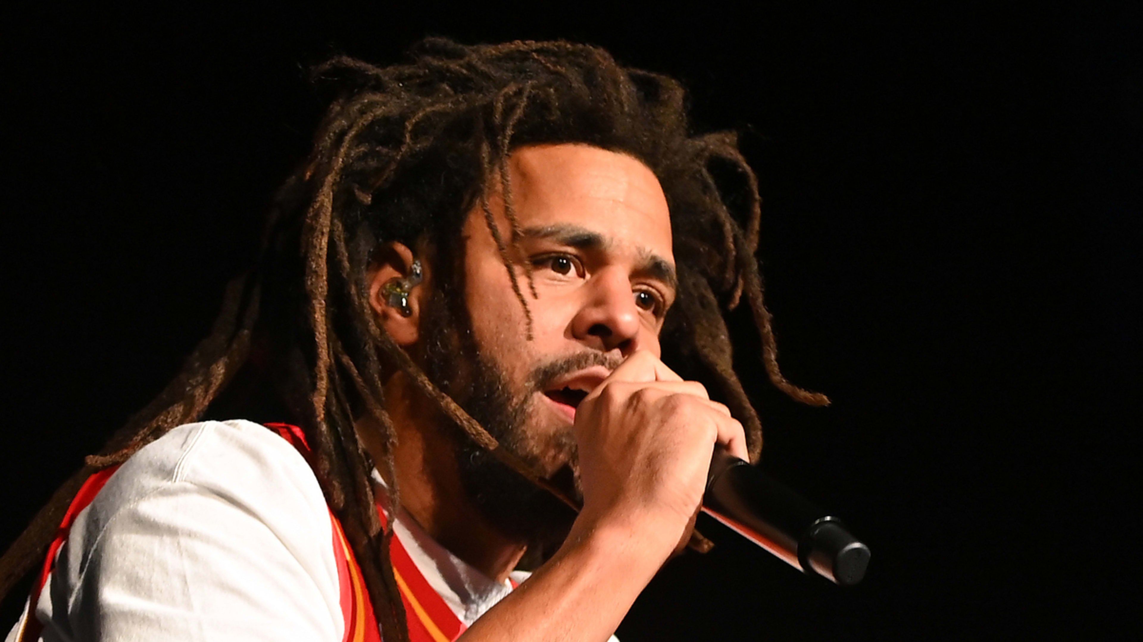 Musician with dreadlocks performing on stage with a microphone