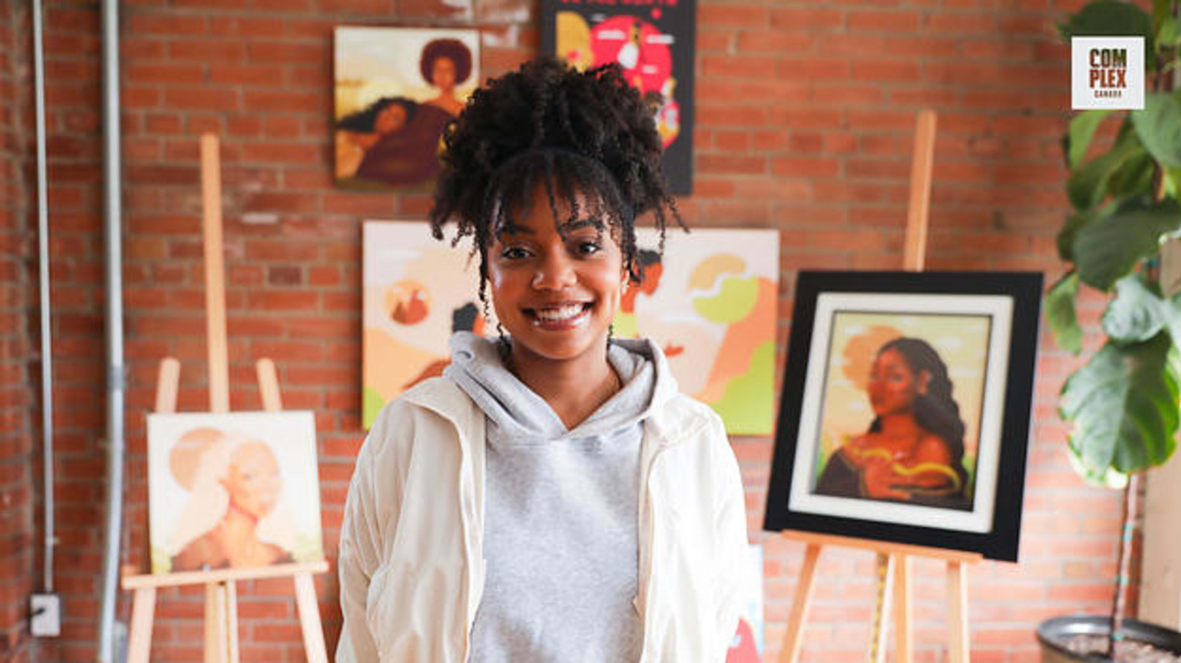 Toronto artist Alexis Exe poses in front of several of her paintings inside her home