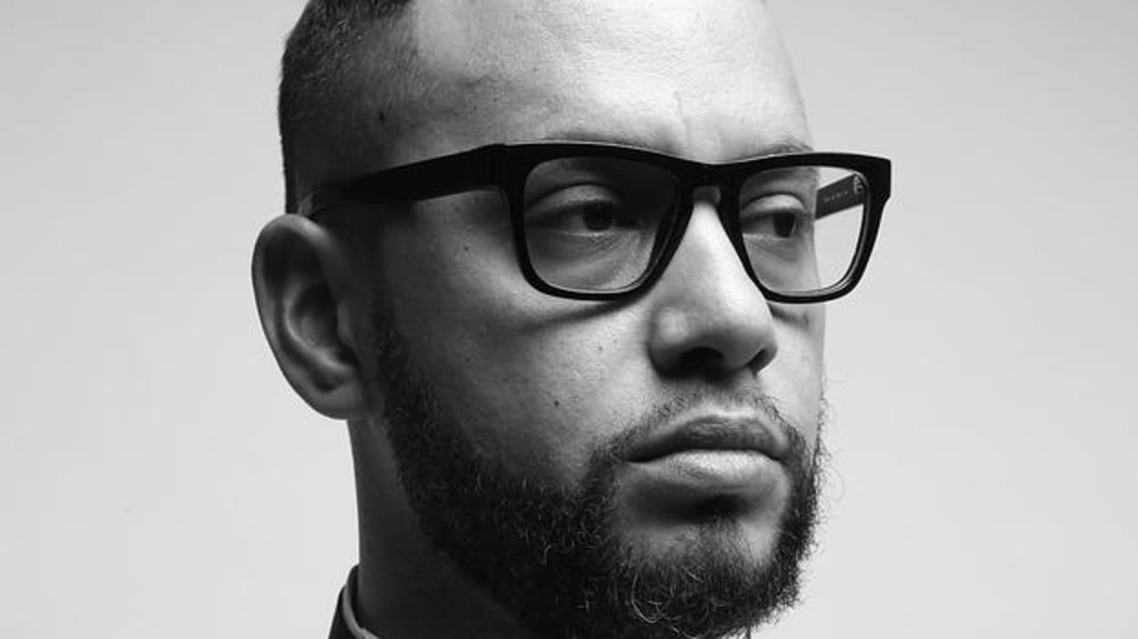 Director X poses in a white shirt and x-shaped tie