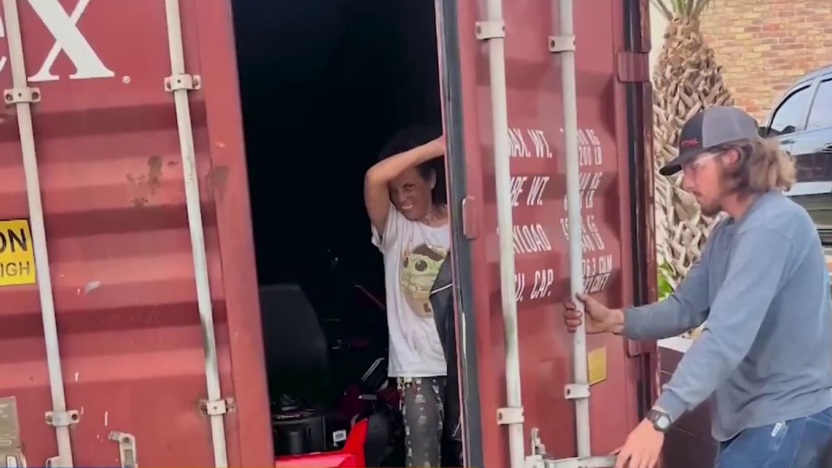 Person inside a shipping container gesturing, another person standing by the open door. Items visible inside