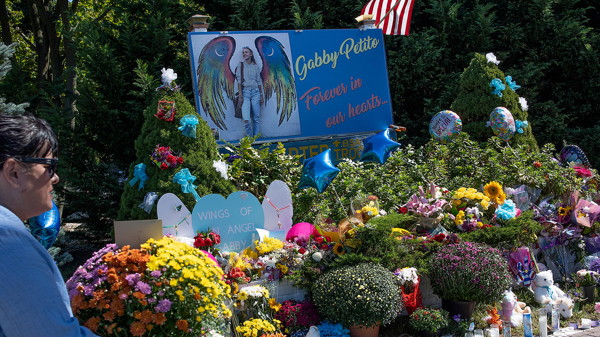 Memorial site with photo of Gabby Petito and "Forever in our hearts" text, surrounded by flowers and tributes