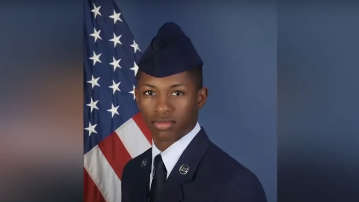 Air Force member in uniform poses before the American flag