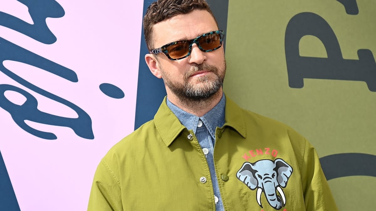 Justin Timberlake in a green Kenzo Paris jacket with an elephant design, wearing sunglasses, at a public event