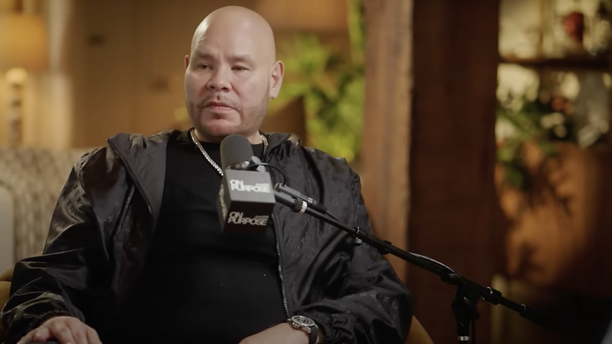 Fat Joe, in a relaxed shirt and jacket, speaks into a microphone during an interview