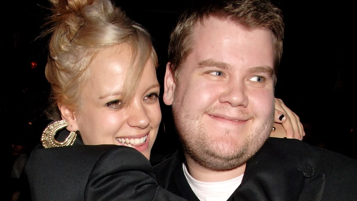 Lily Allen and James Corden smiling and hugging, dressed in stylish black attire at an event
