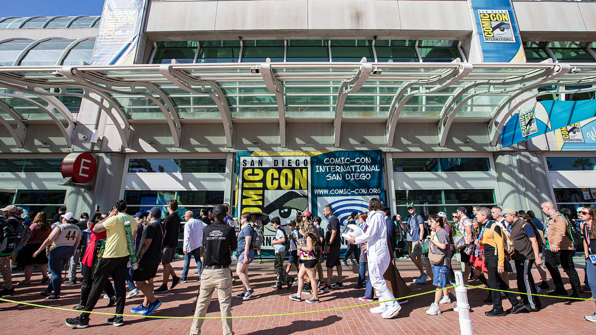 A large crowd stands outside the San Diego Comic-Con International entrance, featuring various attendees in costumes