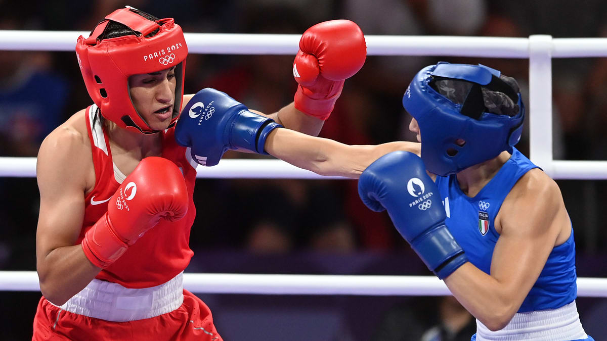 Two boxers, one in red and the other in blue, exchange punches in a match at the Olympics. Both are wearing headgear and gloves