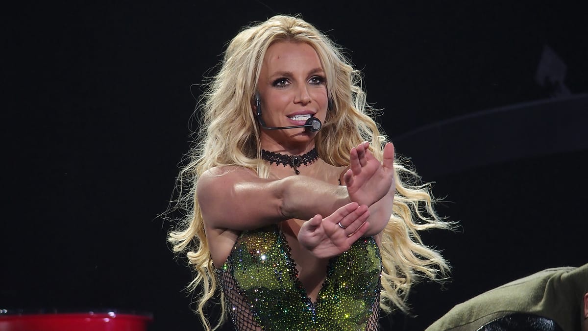 Britney Spears performing on stage with a headset microphone, wearing a sparkling, sequined outfit