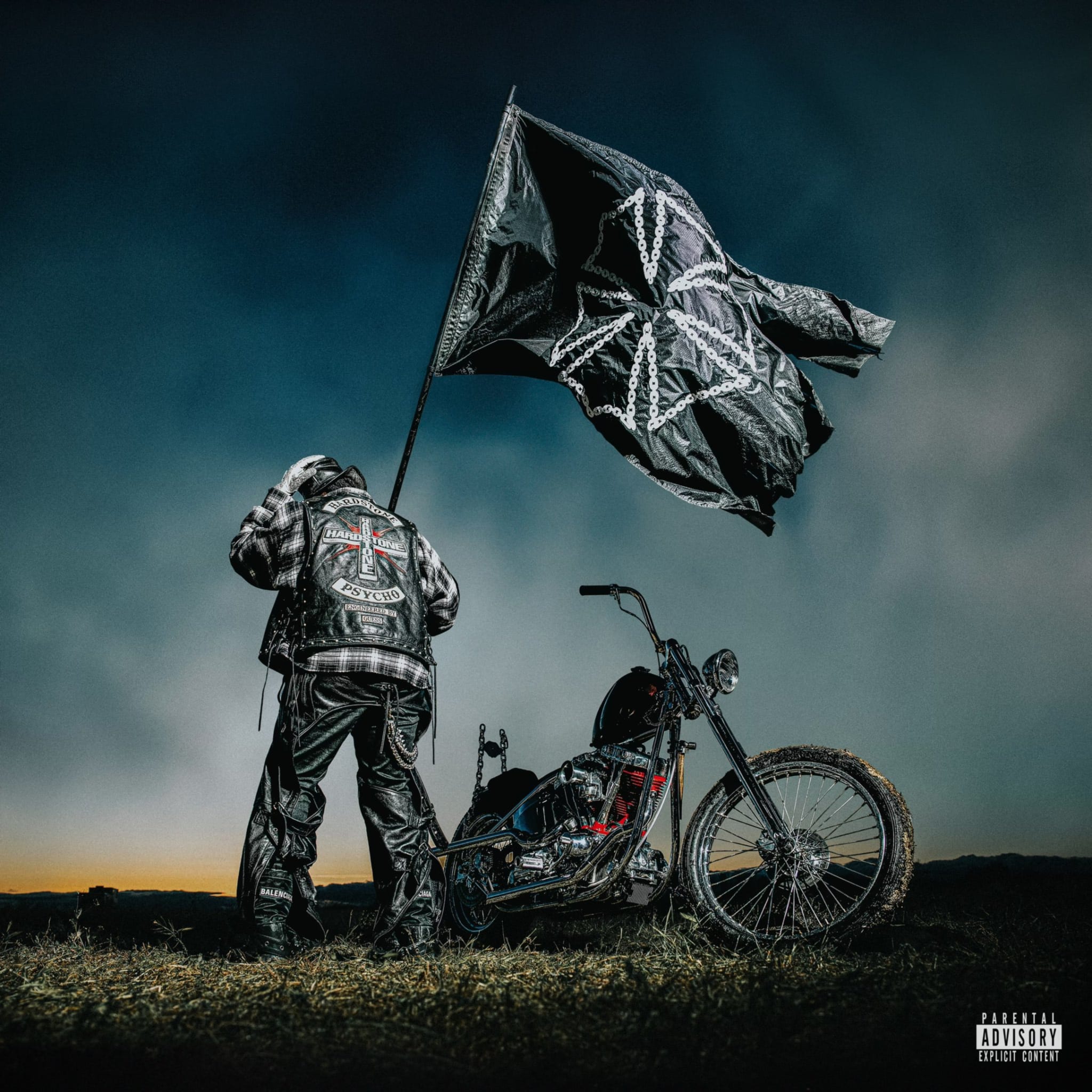 A person in a leather jacket stands by a custom motorcycle, holding a large flag with a unique symbol. The image is associated with music