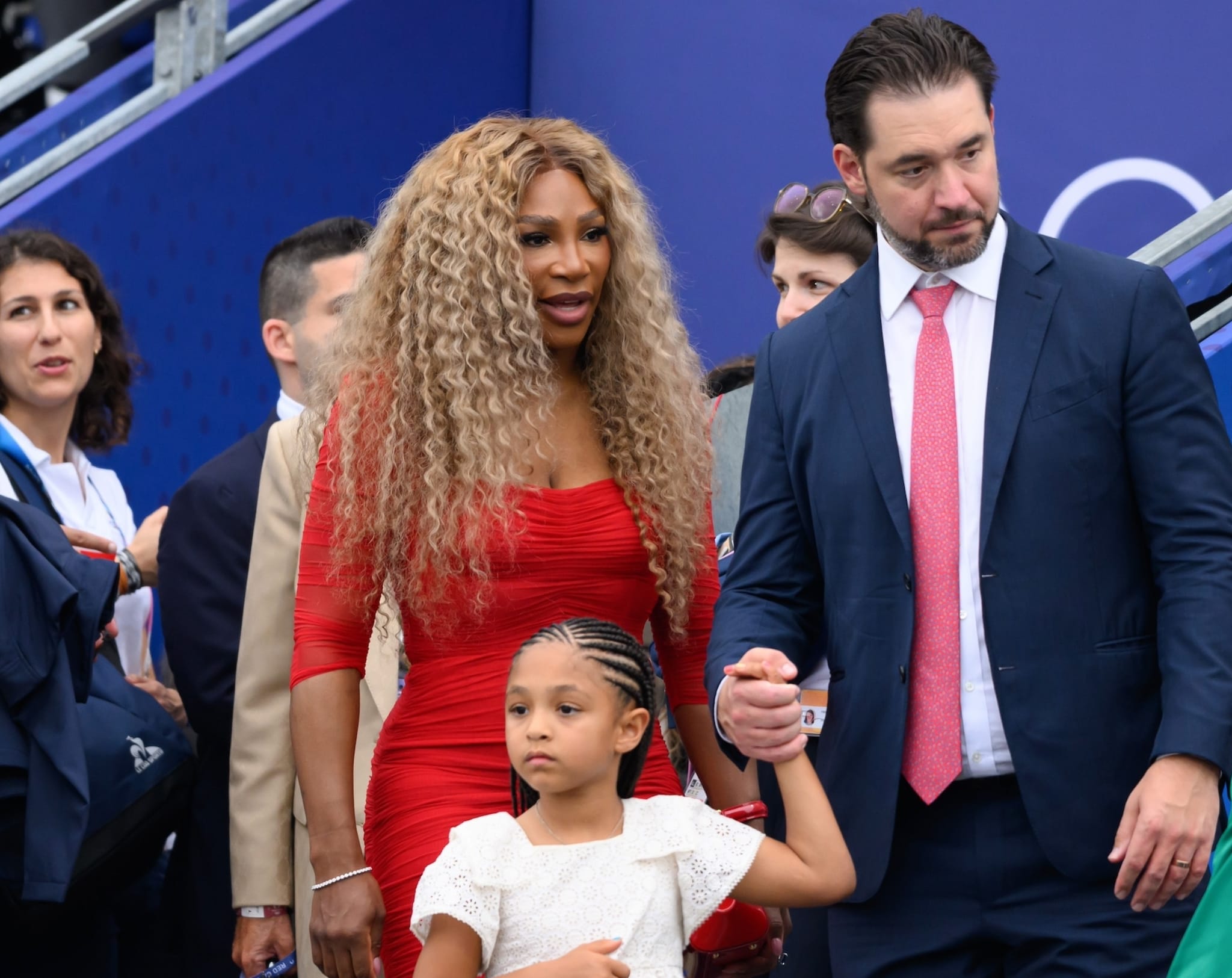 Serena Williams in a form-fitting dress, holding hands with Alexis Ohanian and their daughter Alexis Olympia Ohanian Jr., walking at an outdoor event