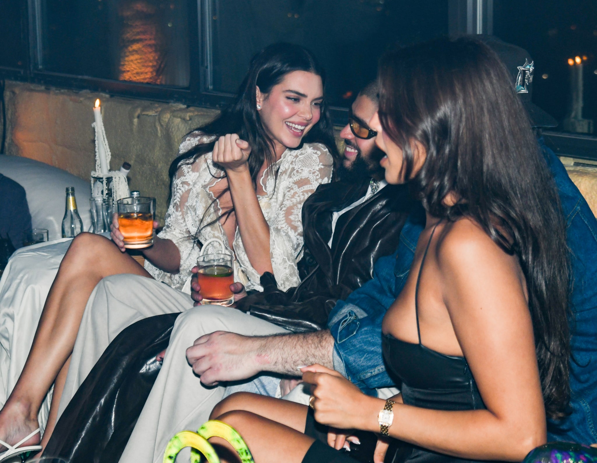 Three people lounging, one in a leather jacket, interacting joyfully