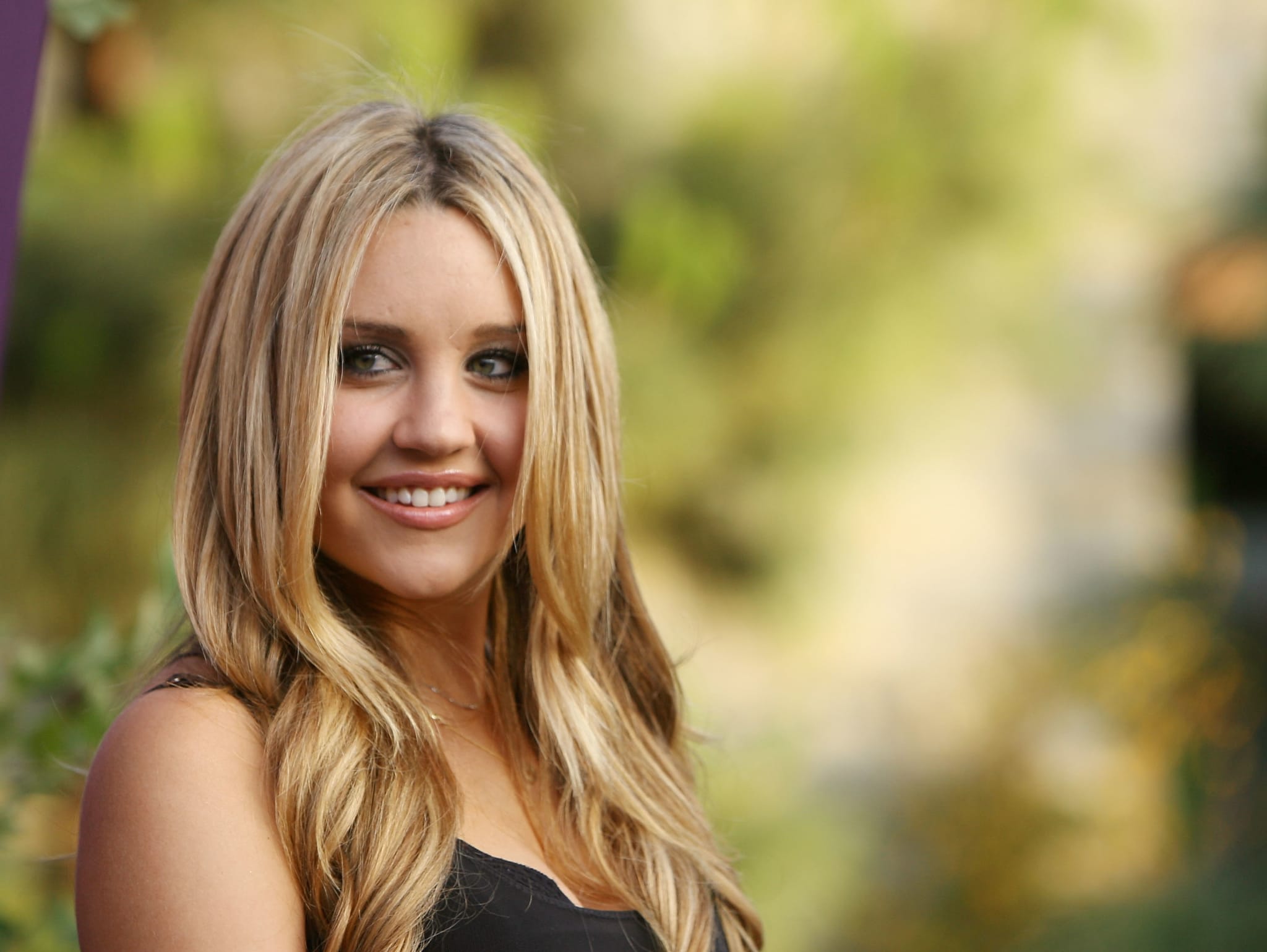 Woman with blonde hair wearing a V-neck top, smiling outdoors