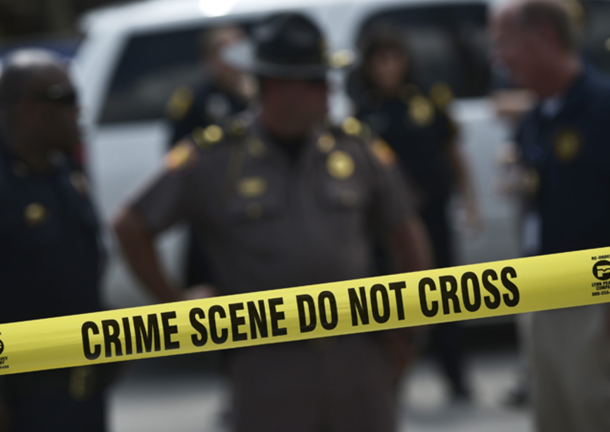 Police stand behind a crime scene tape