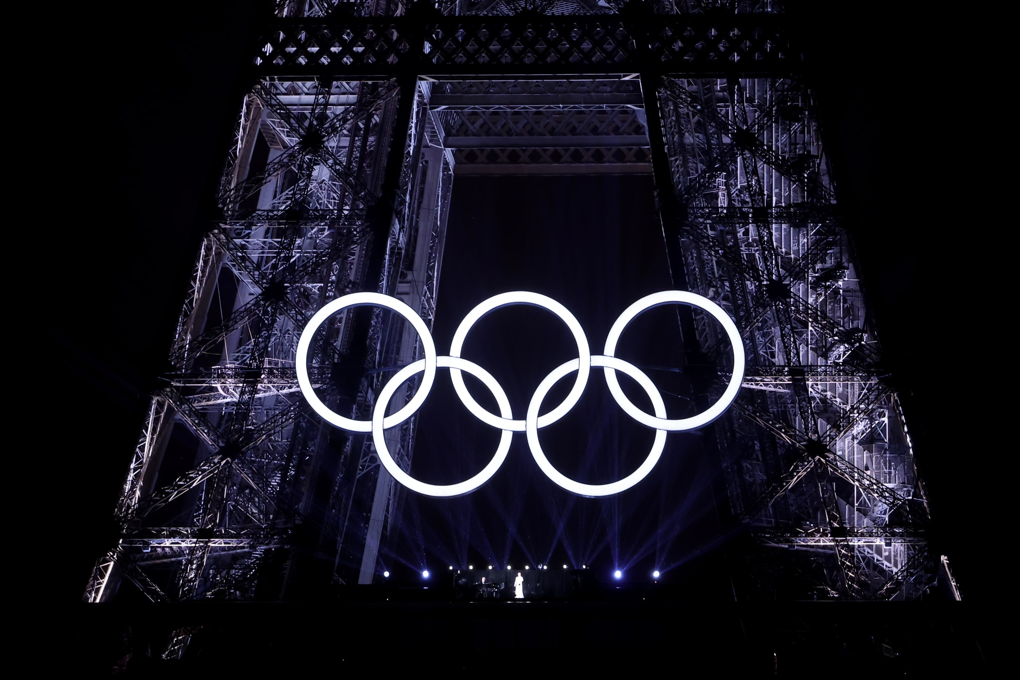 Olympic rings illuminated and displayed at the Eiffel Tower in celebration of the upcoming Olympic Games. No persons are visible in the image