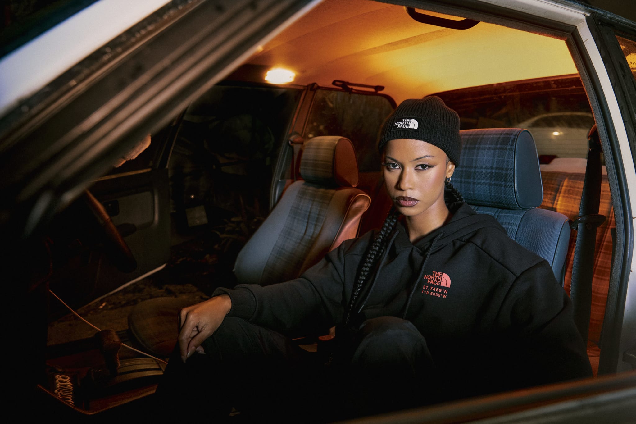 A woman in a beanie and casual attire sits inside a car