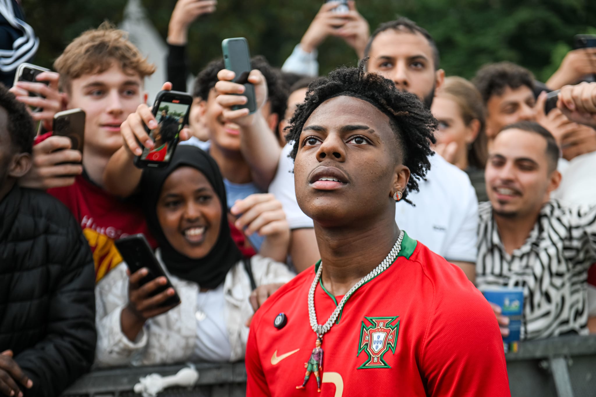 IShowSpeed wearing a Portugal jersey, surrounded by excited fans taking photos and selfies outdoors