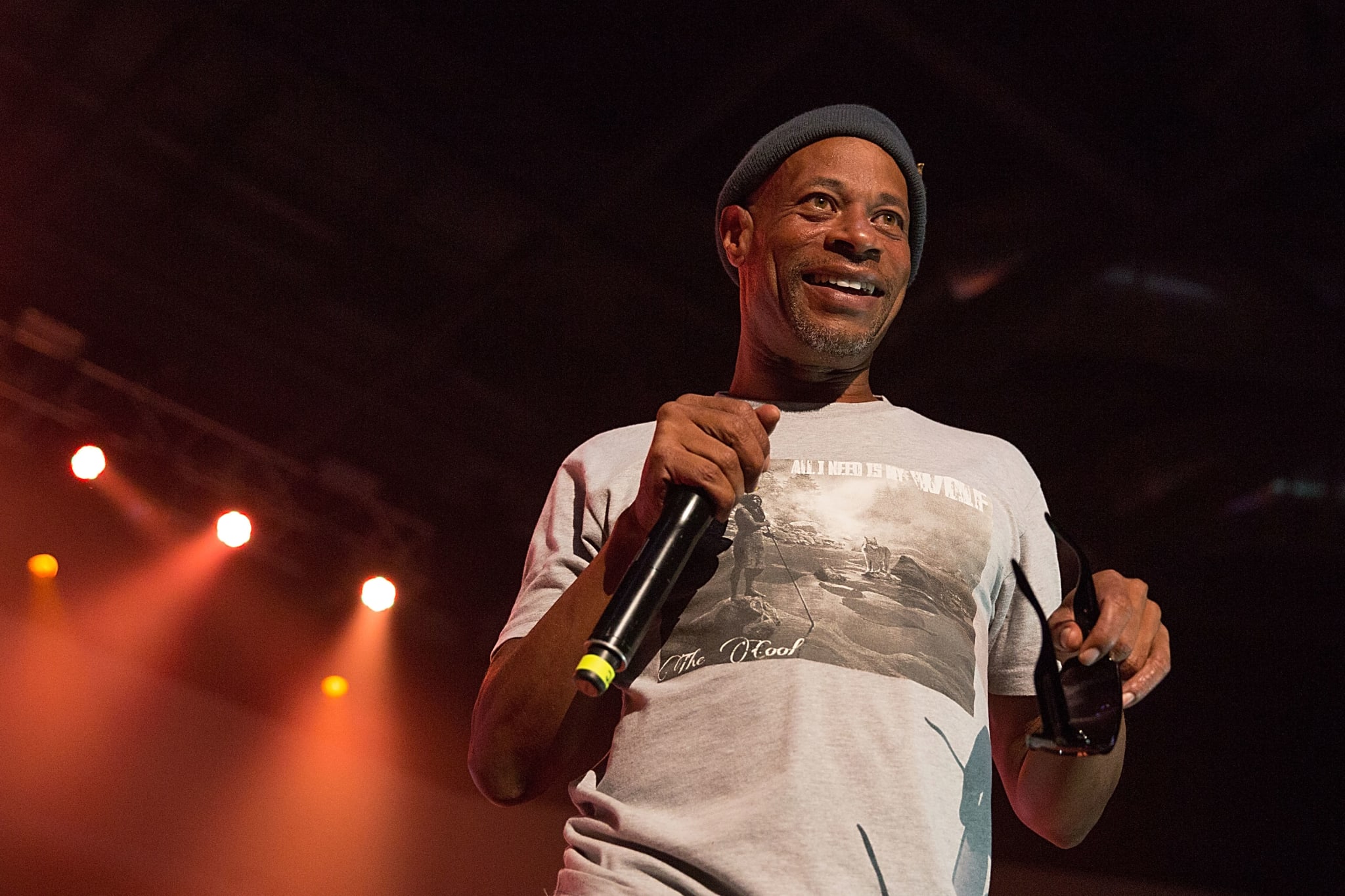 Rapper Brother Marquis of 2 Live Crew holding a microphone and sunglasses, smiling at an audience while speaking