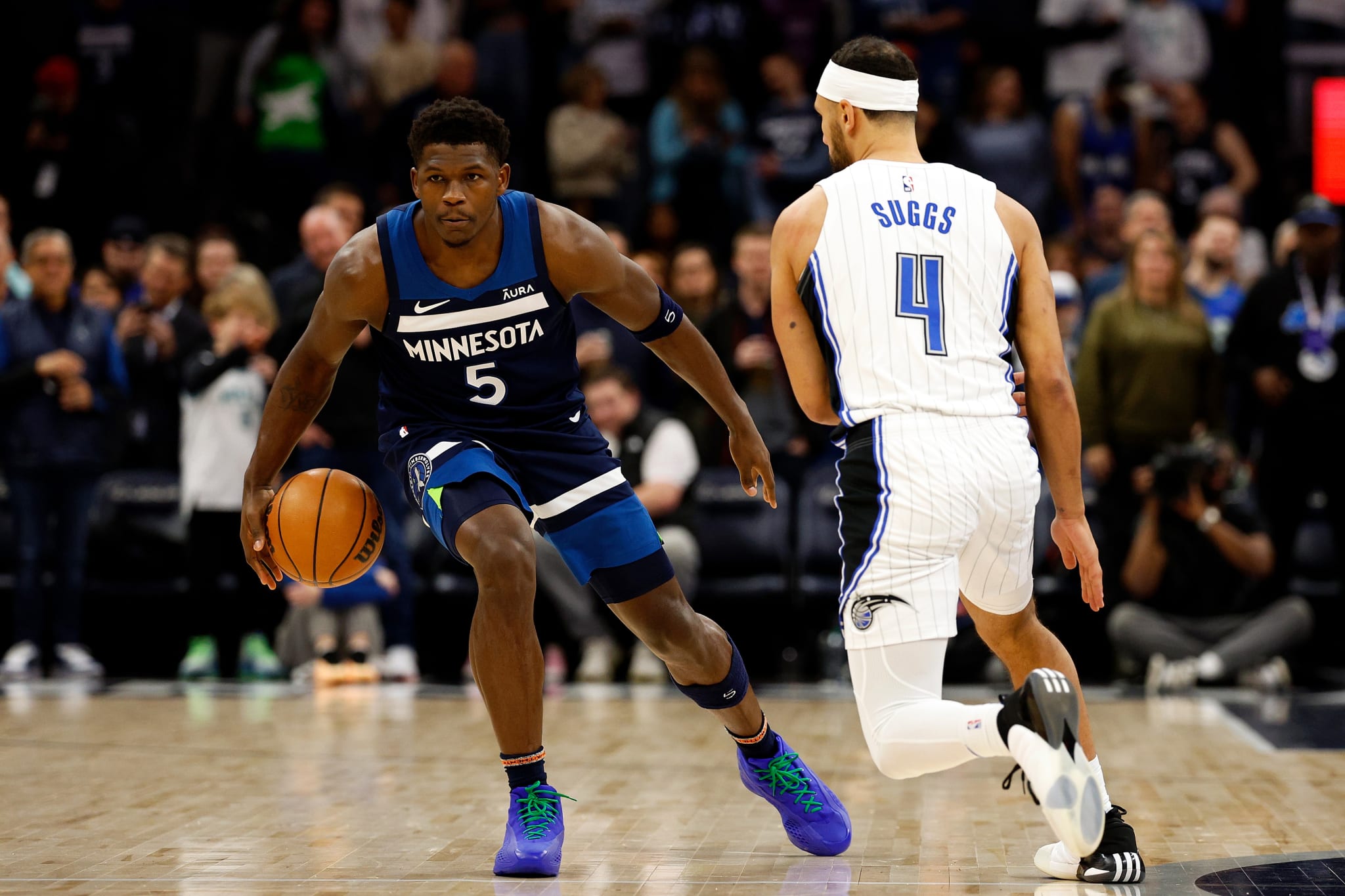 Two basketball players in action during a game, one from Minnesota team dribbling past an Orlando player