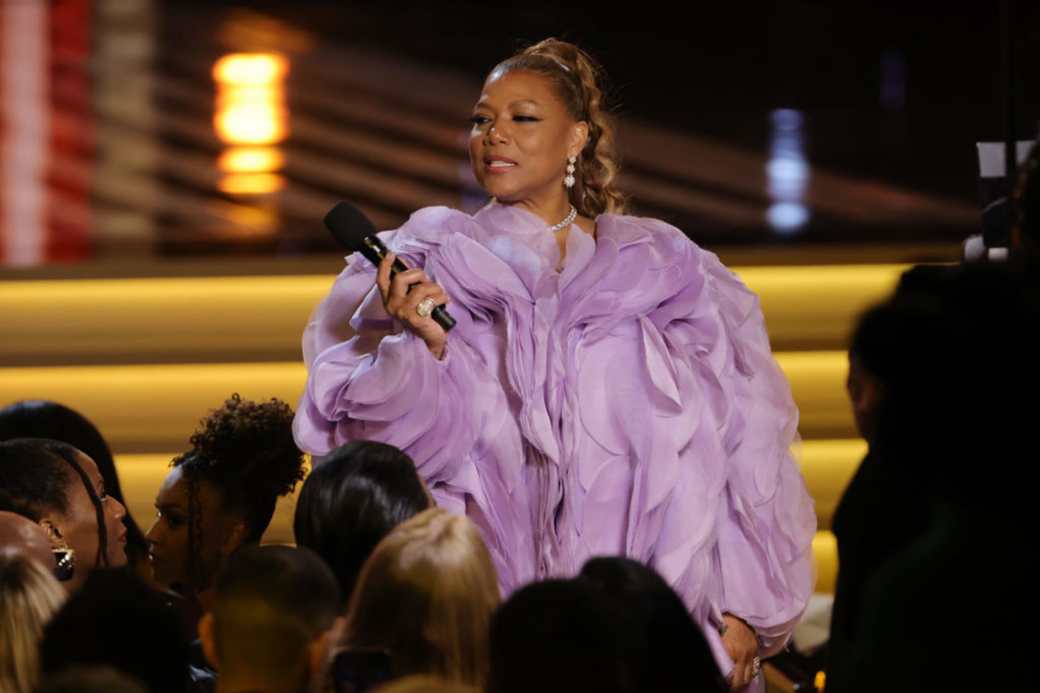 Person on stage with microphone wearing billowing purple attire