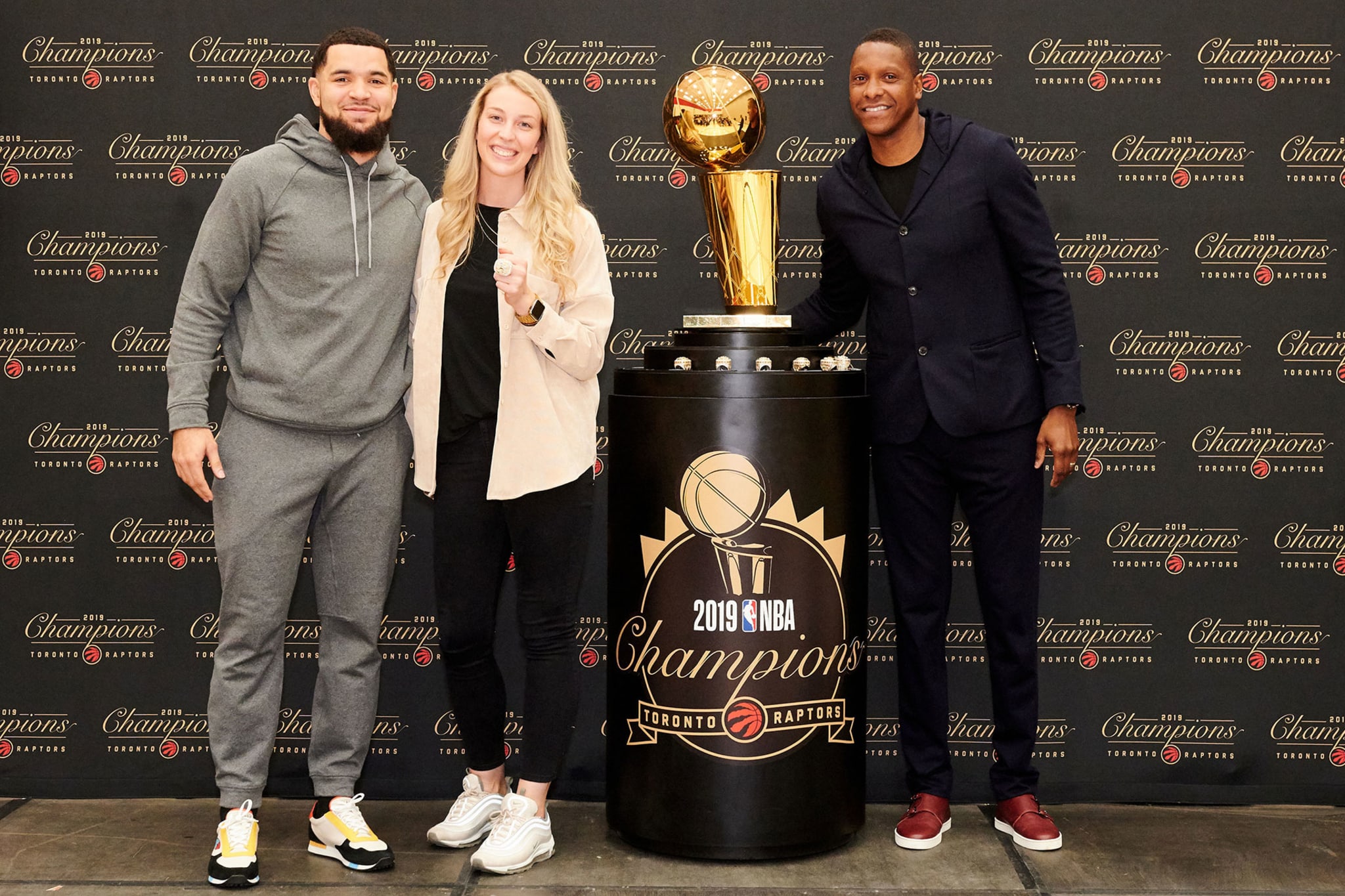 Toronto Raptors' Shelby Weaver poses with Fred VanVleet, Masai Ujiri, and the Larry O'Brien trophy
