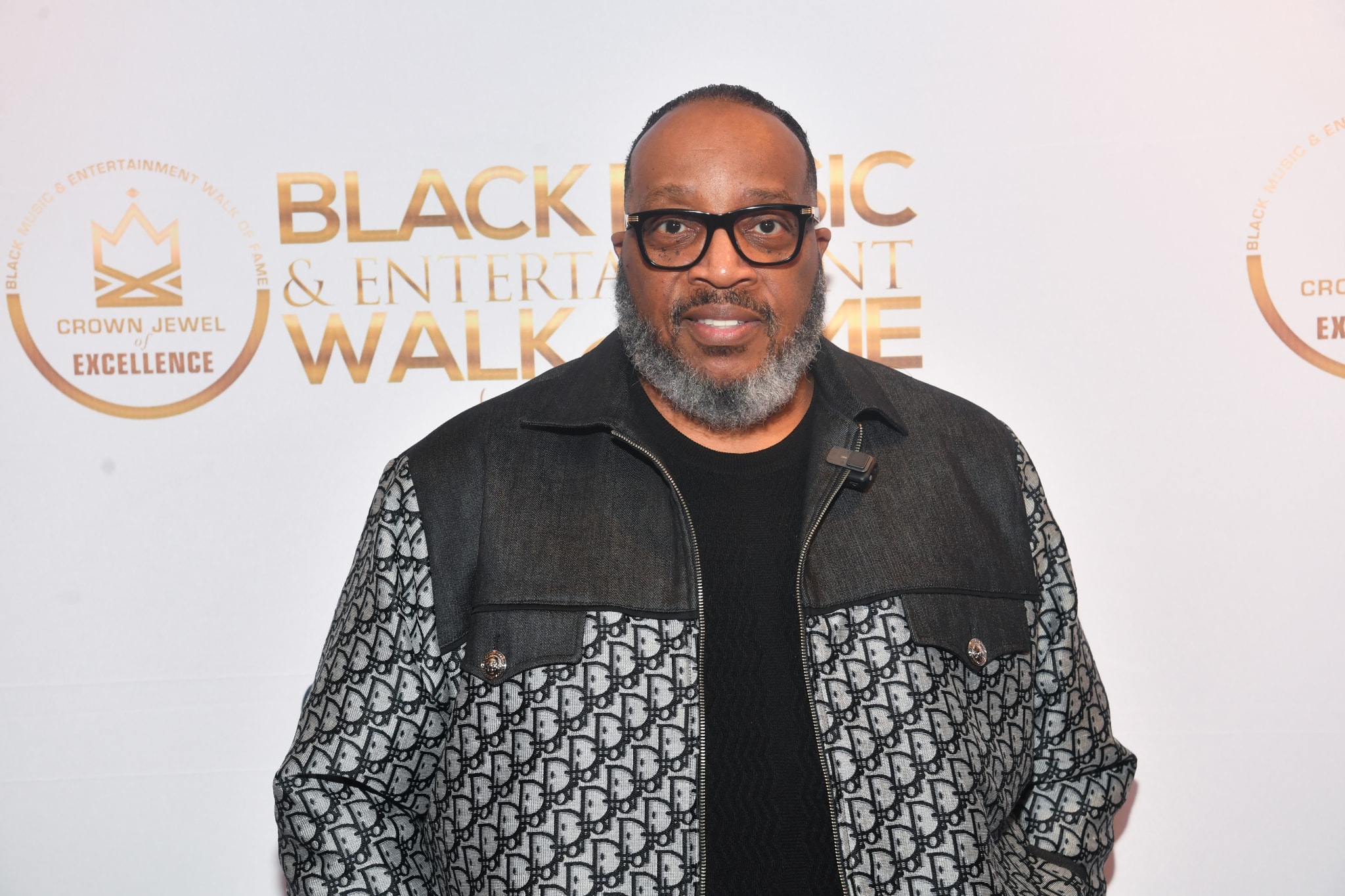 Marvin Sapp with glasses and a beard stands in front of a backdrop.