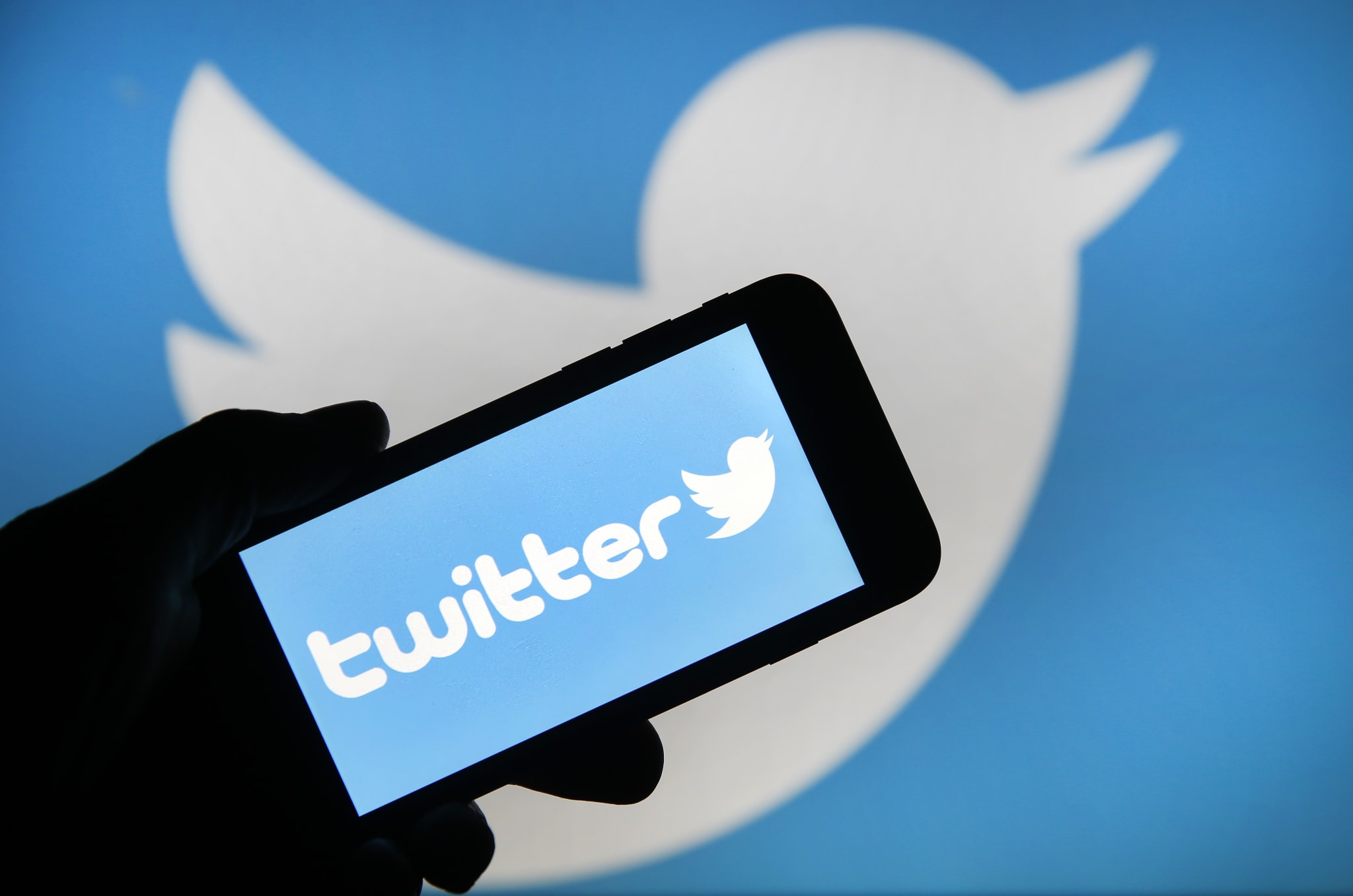 Twitter on a phone with the logo behind