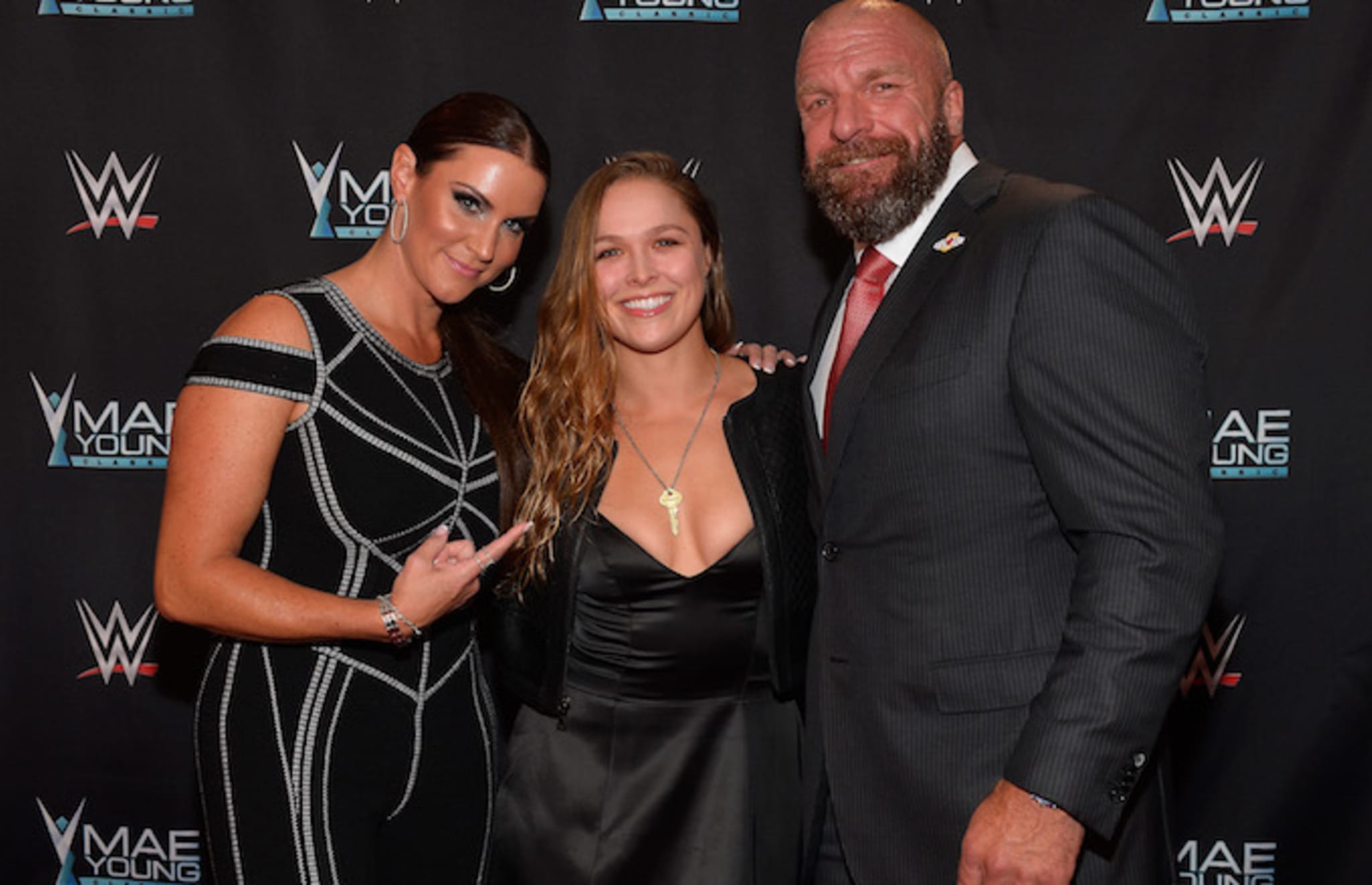 Stephanie McMahon, Ronda Rousey, and Triple H appear on the red carpet.