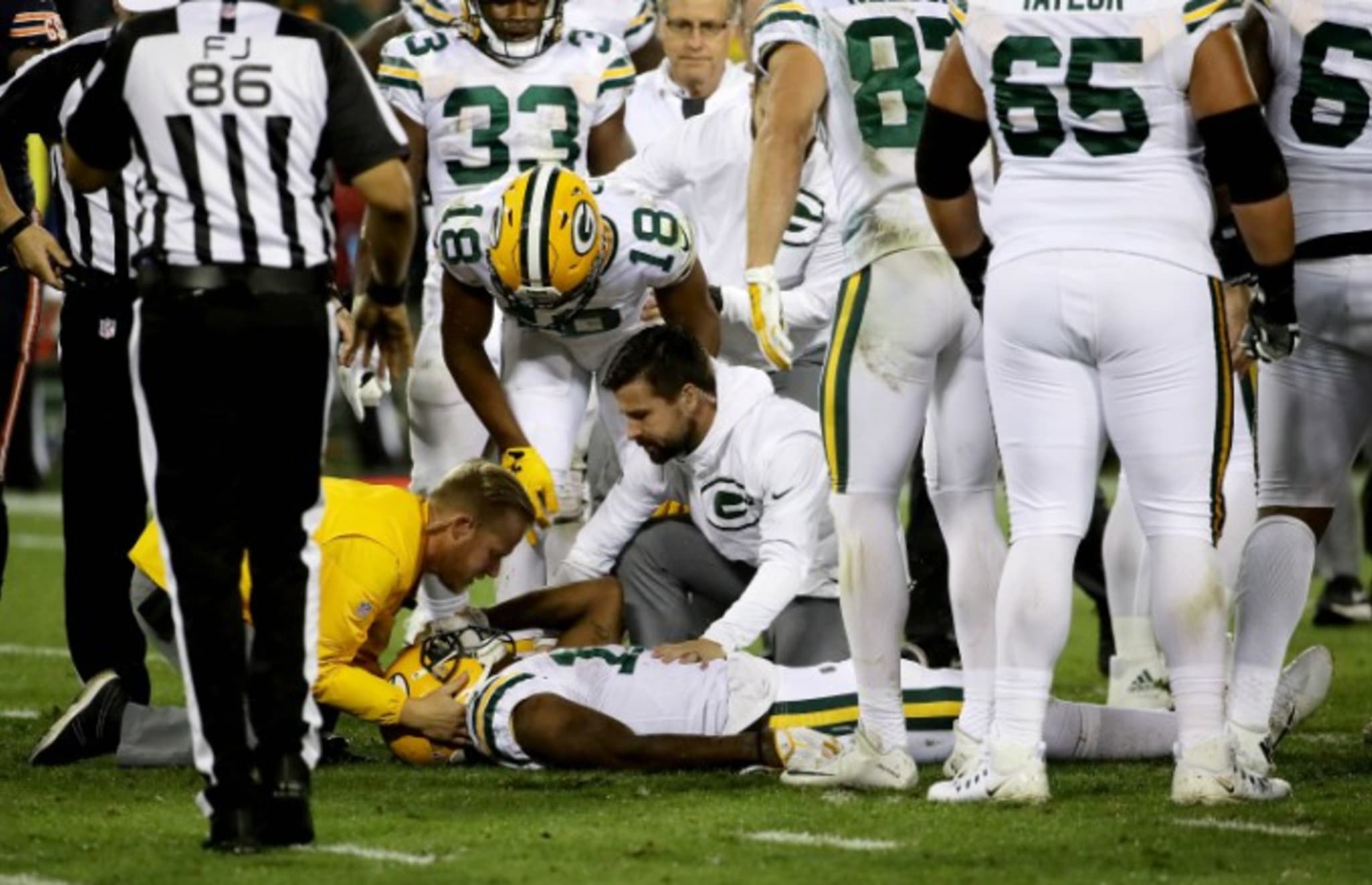 Davante Adams receives medical attention on the field.