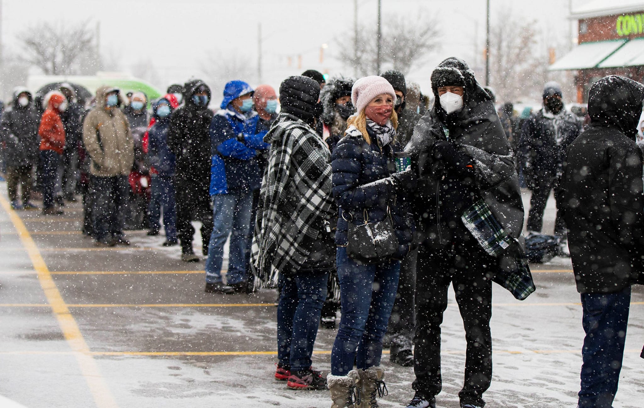 People wearing face masks line up to pick up free COVID-19 antigen rapid test kits in Mississauga
