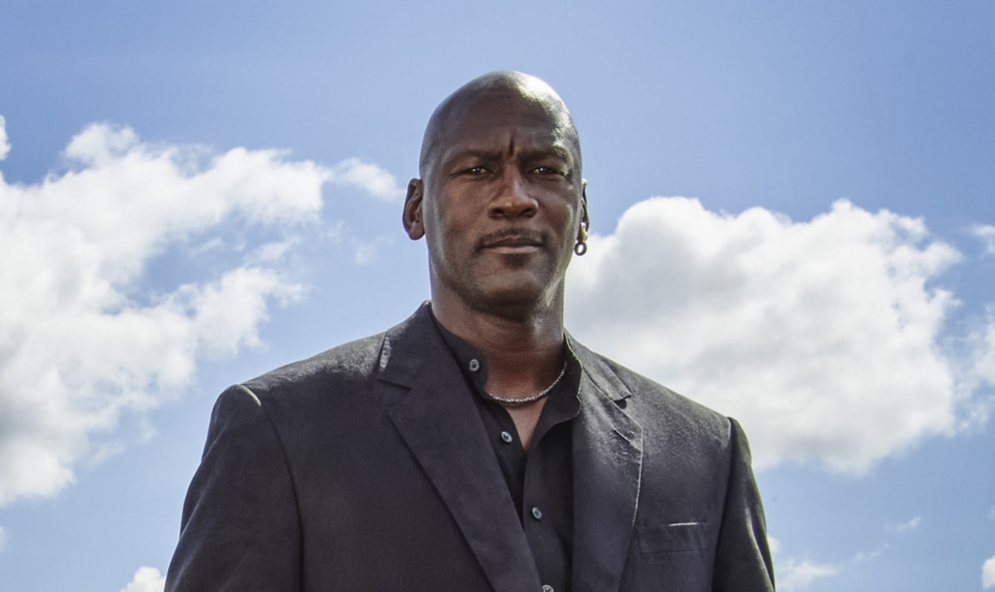 Michael Jordan in a suit in front of a blue sky