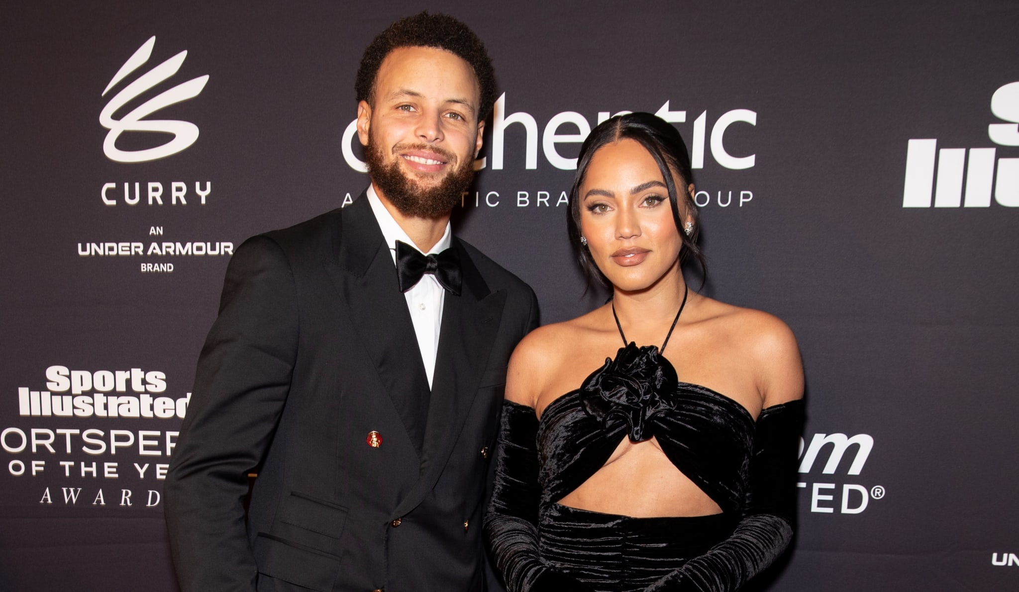 Stephen Curry and Ayesha Curry smiling in formal attire at a Sports Illustrated event