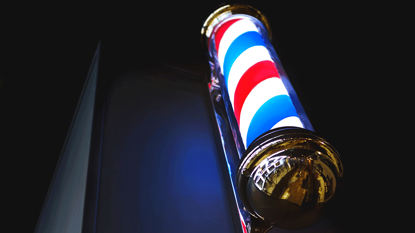 A low angle shot of a barber shop pole at night.