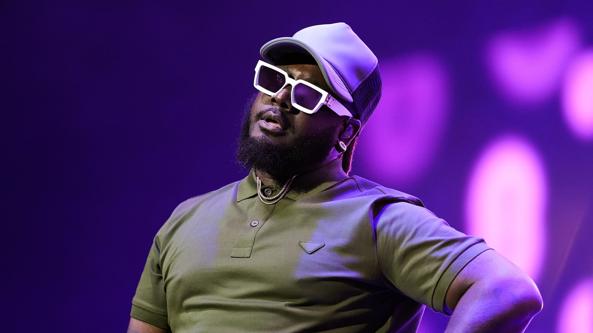 T-Pain on stage, wearing a hat, white sunglasses, and a polo shirt