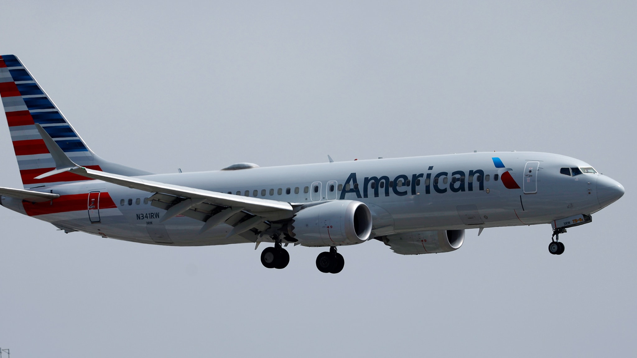 American Airlines airplane in mid-air preparing for landing. The aircraft features the company's logo and branding on its side and tail