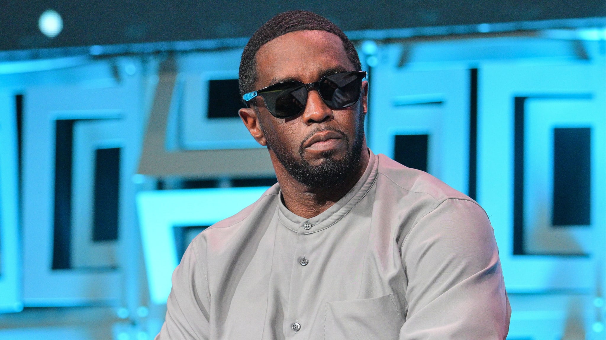 Sean "Diddy" Combs wears sunglasses and a casual button-up shirt while attending an event