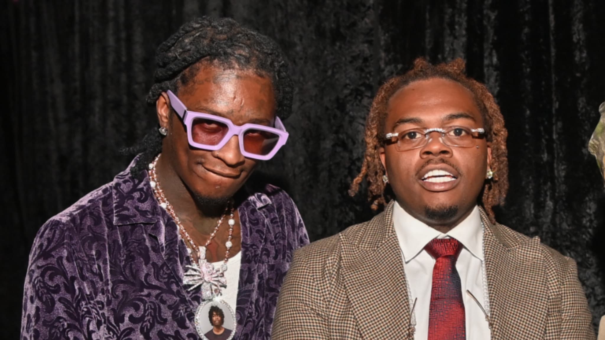 Young Thug in a patterned jacket and Gunna in a suit with a red tie at a music event